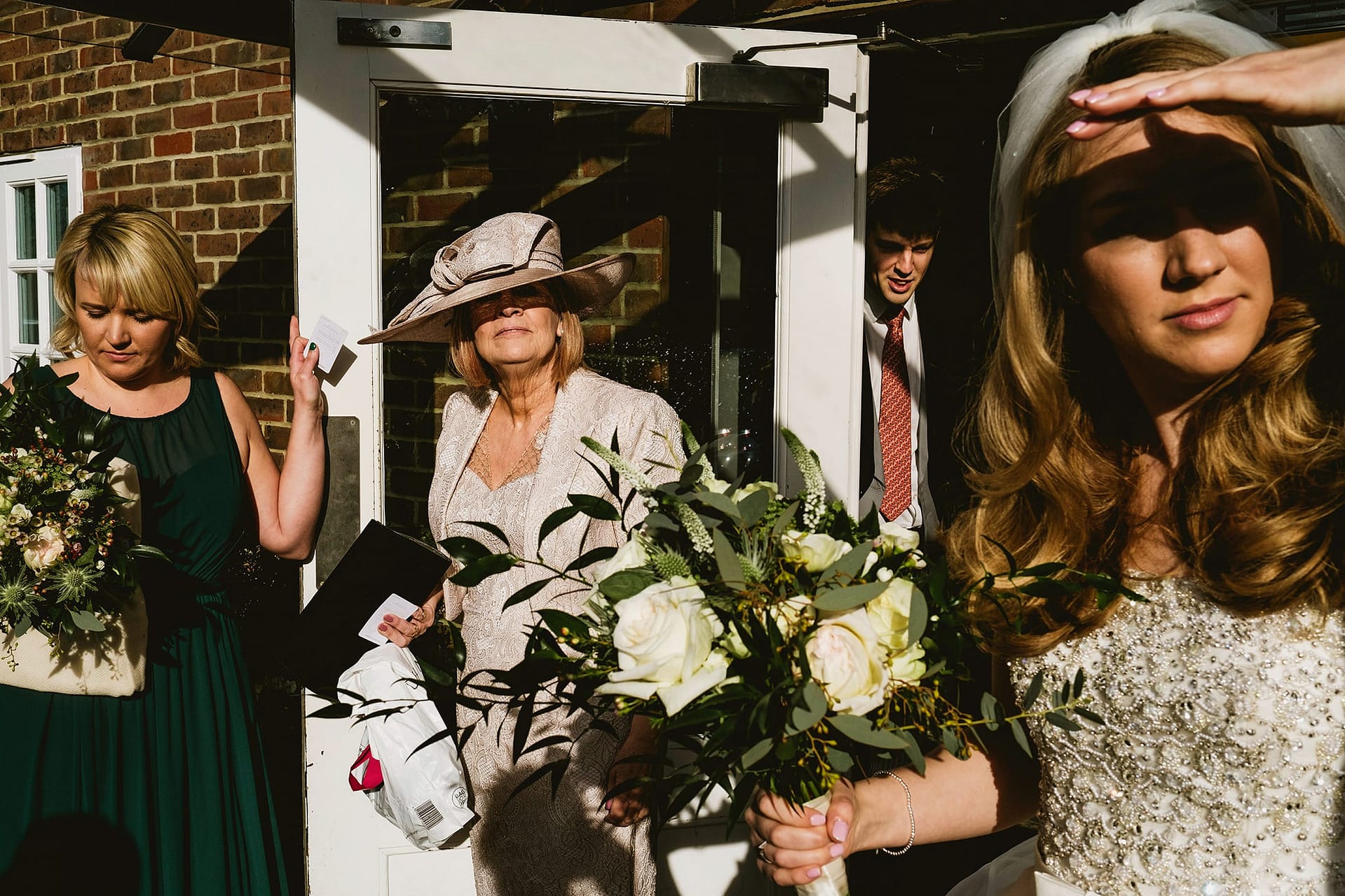 Light and shadow at Northbrook Park. Bride shielding her eyes in the harsh light.