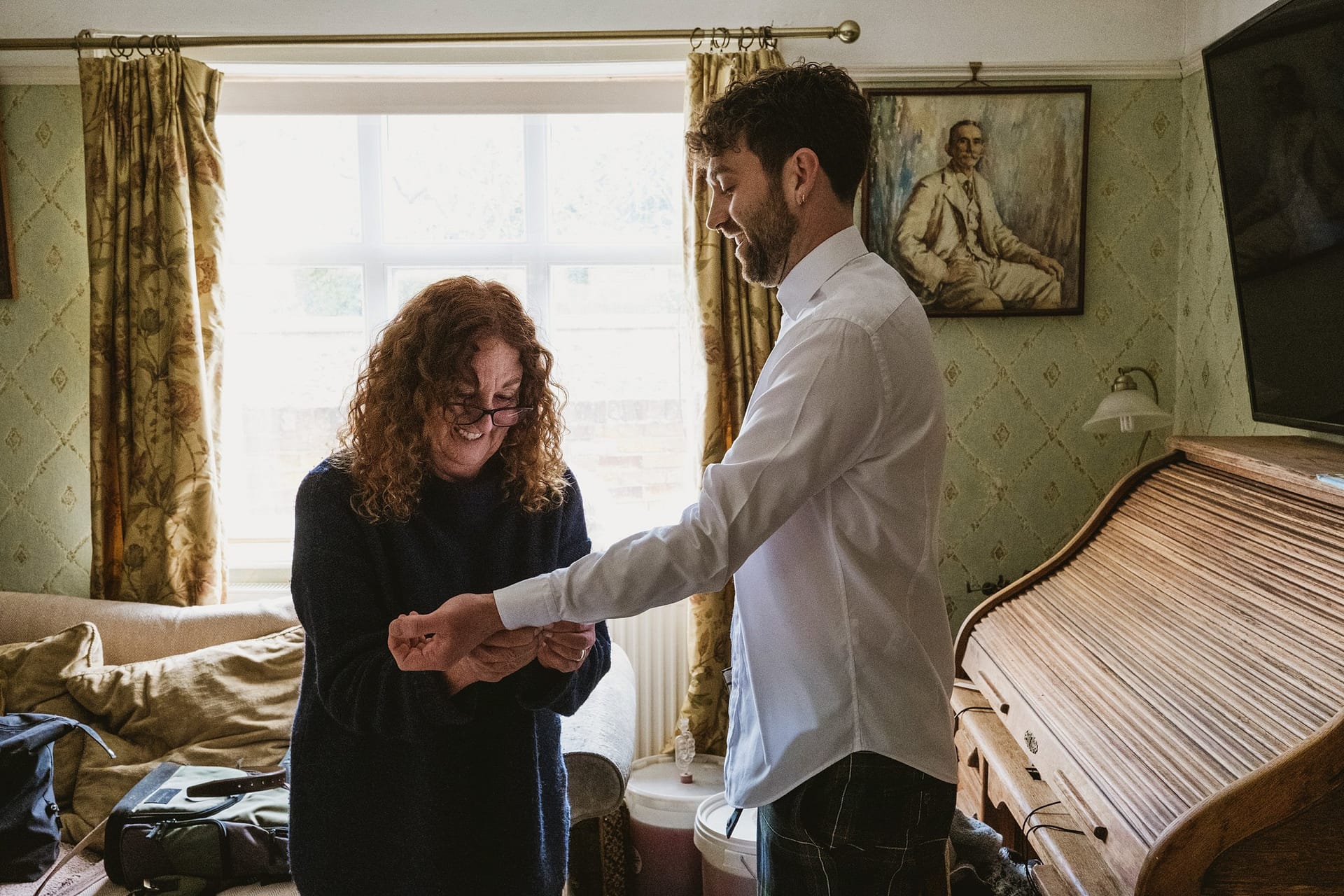 groom having his cufflinks put on by his mother in suffolk