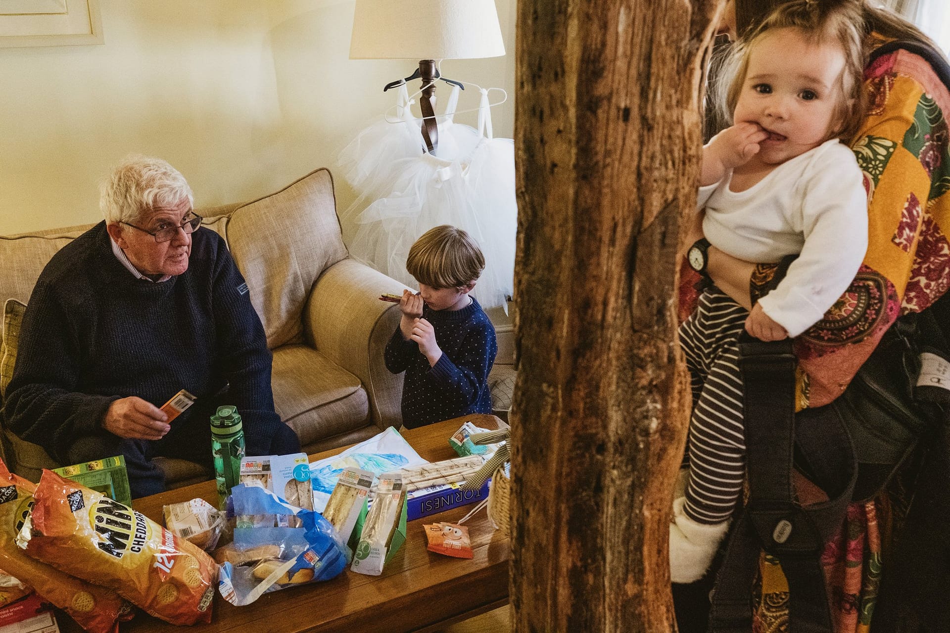 baby girl looking at camera, granddad looking after grandson who is drawing in suffolk