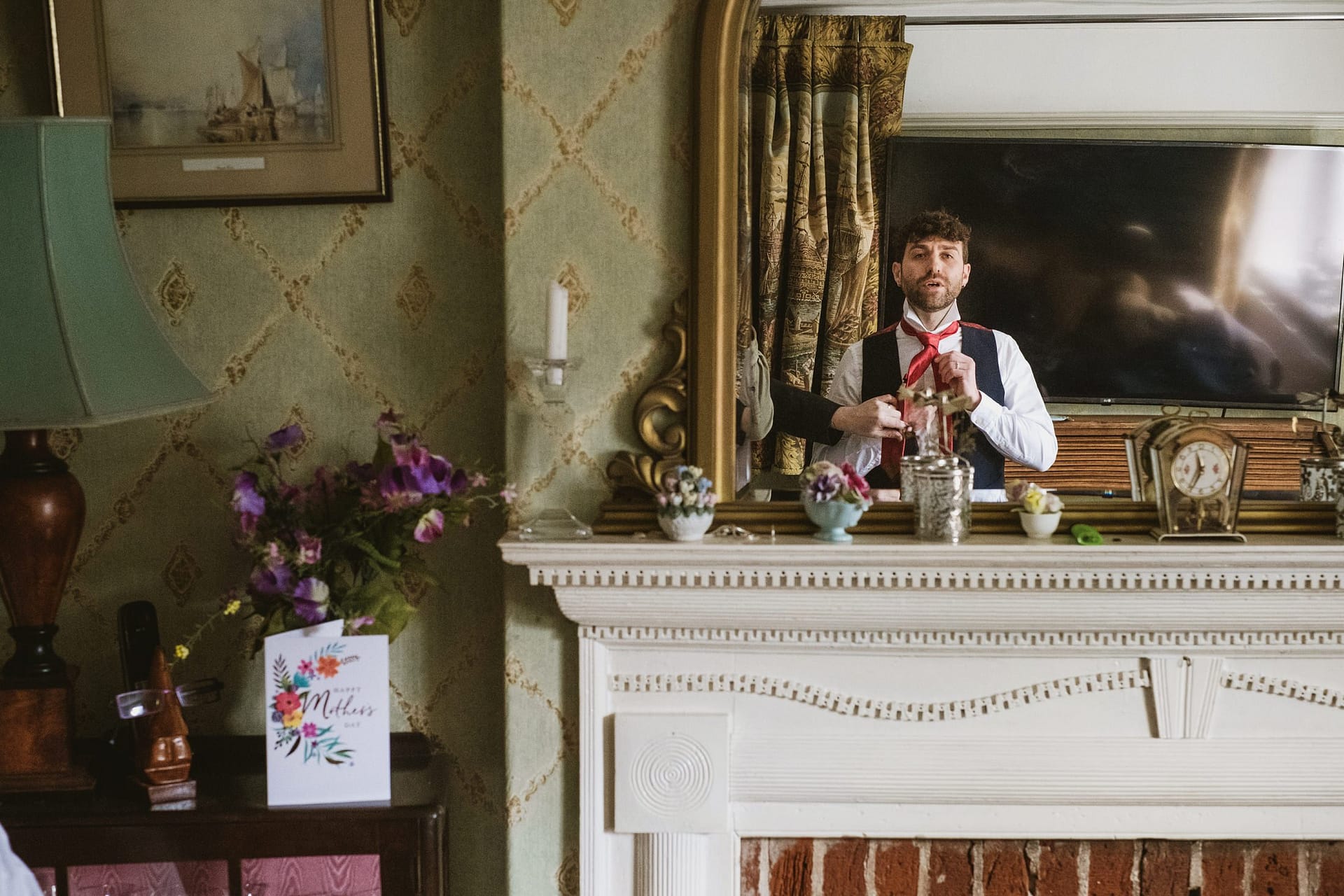 groom putting his tie on in the mirror at Alpheton Barns