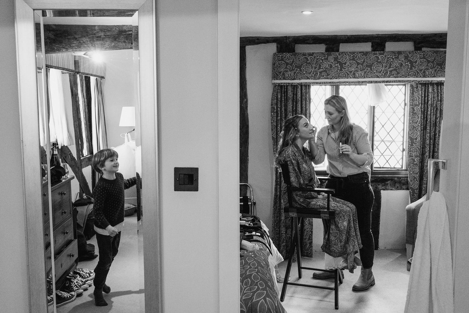 bride having her make up done with little boy watching from next room in suffolk