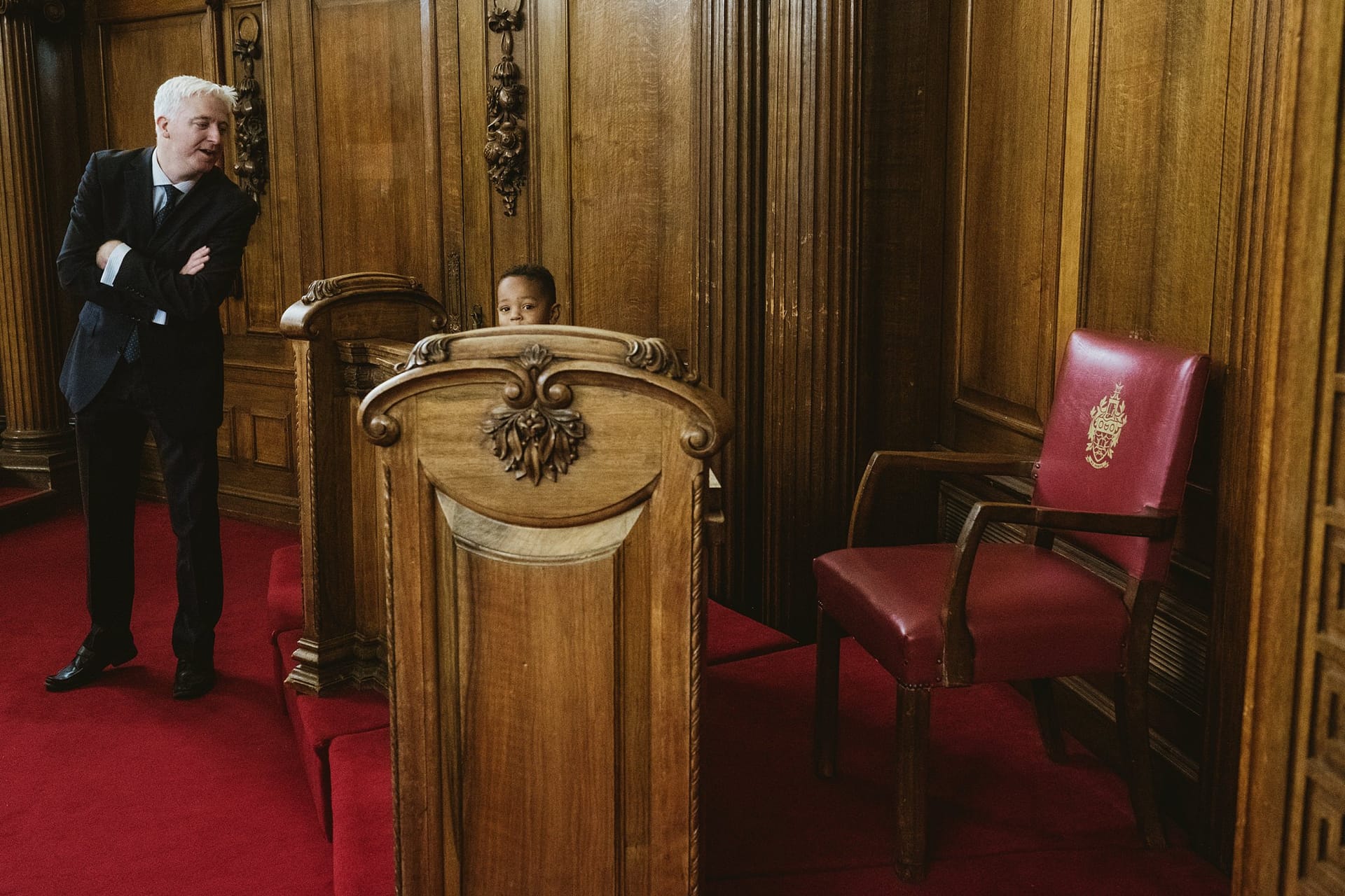 page boy playing in the chairs with grandad watching at Islington Town Hall