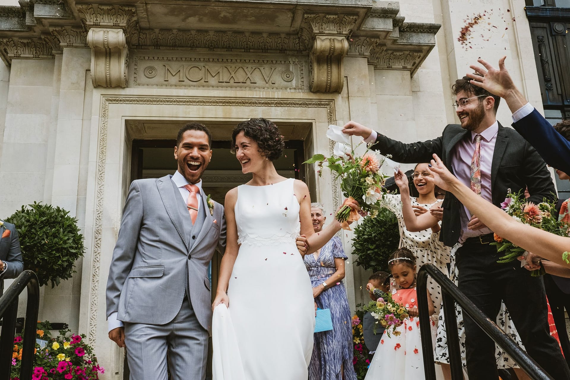 bride and groom walking down steps to confetti at Islington Town Hall
