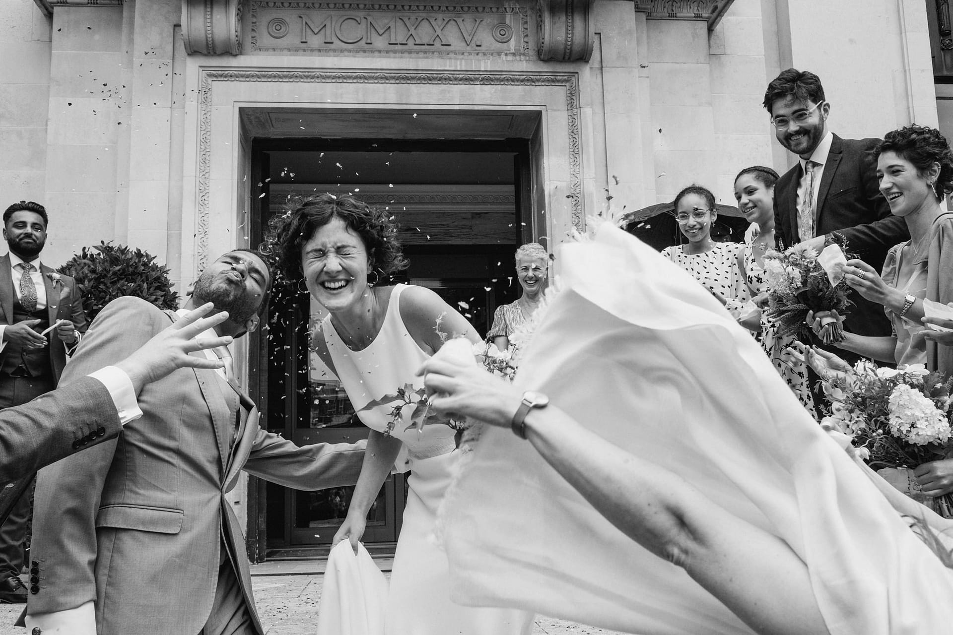 bride laughing with groom as confetti is thrown at Islington Town Hall in london