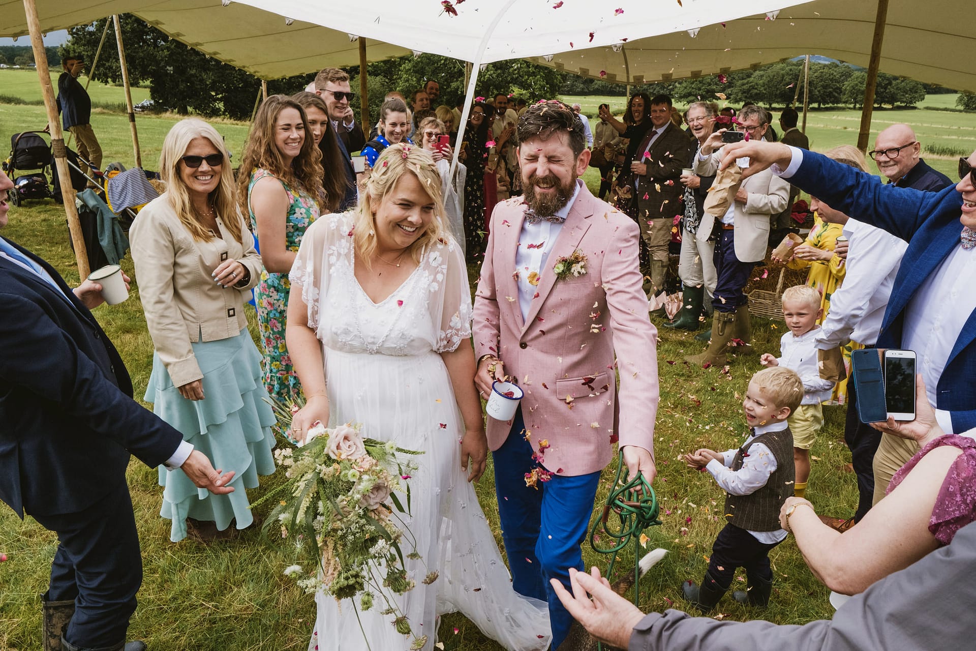 Wedding couple celebrating with guests outside tent.
