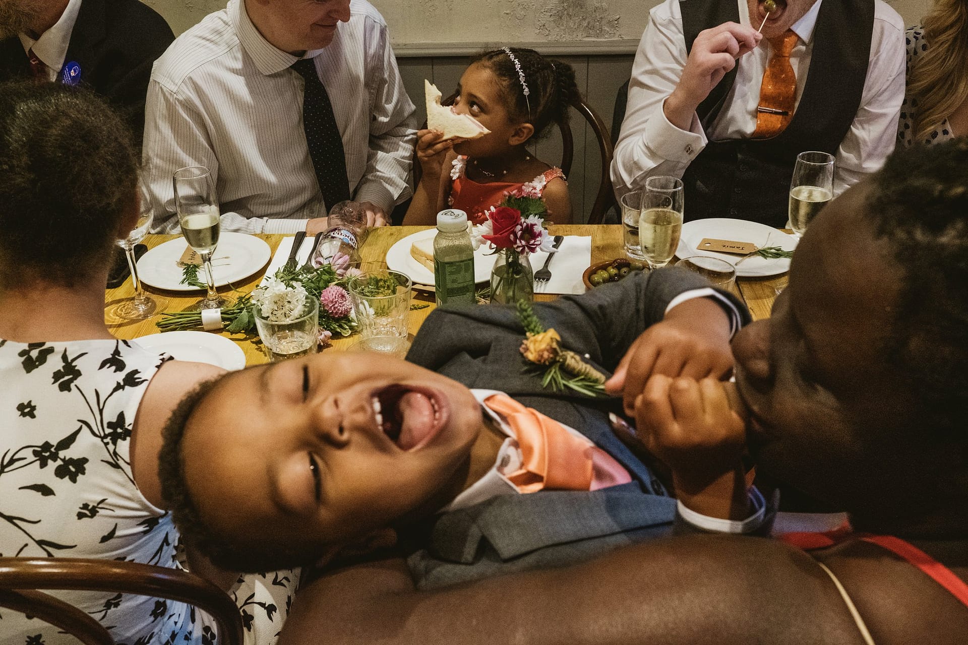 La Farola restaurant dining flower girl holding a sandwich over her face and page boy singing in mothers arms