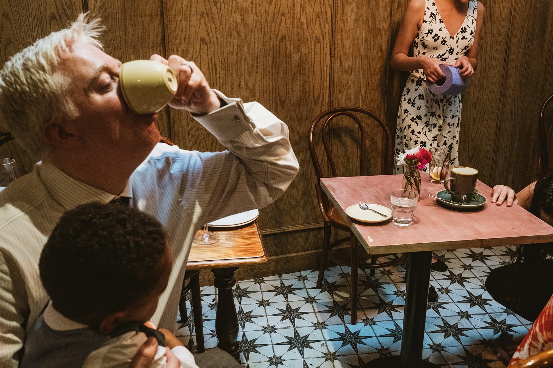 wedding guest drinking coffee with wedding guest in background at La Farola restaurant