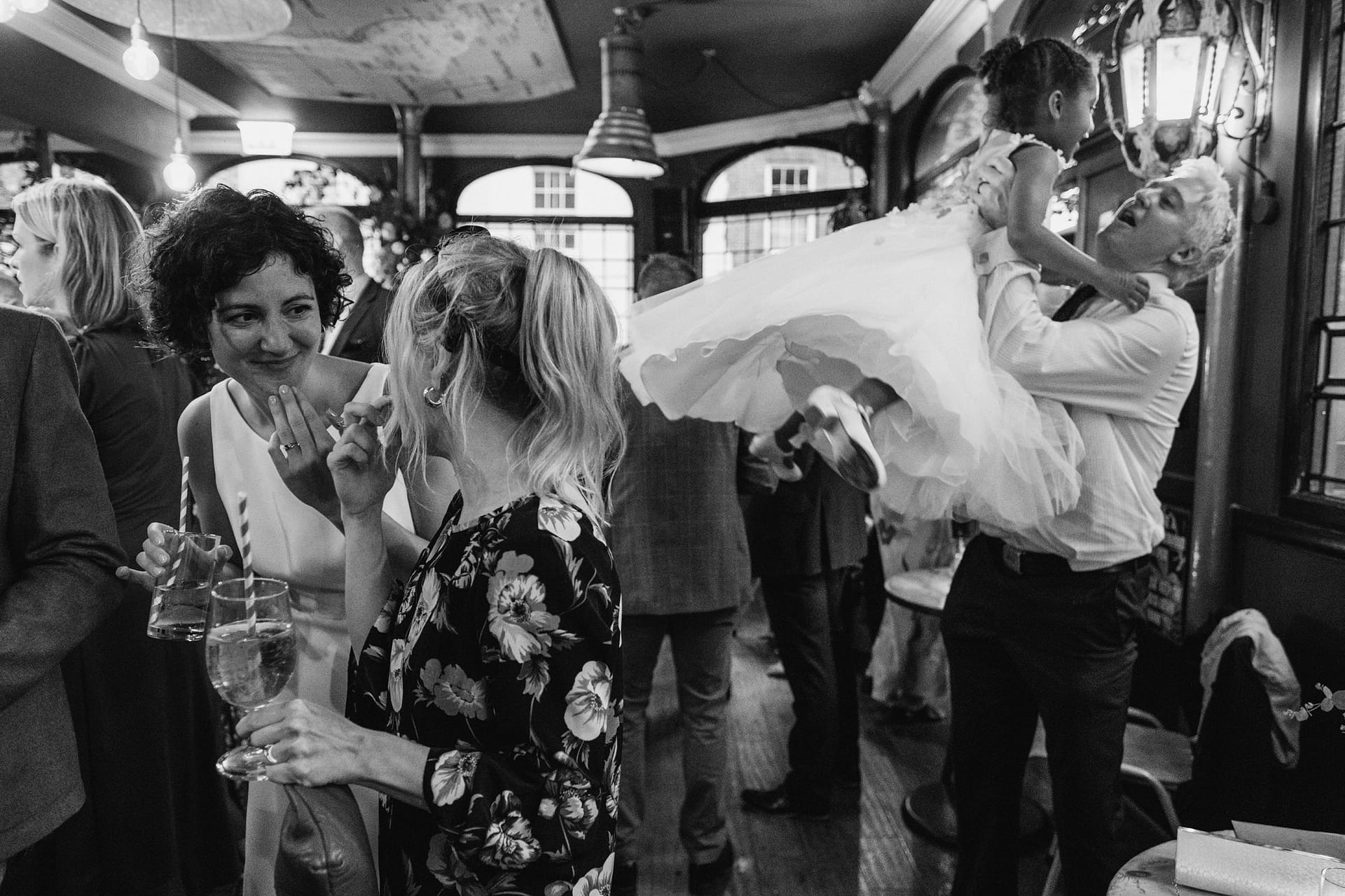 bride chatting with friend whilst flower girl lifted in the air at Prince Albert pub in london