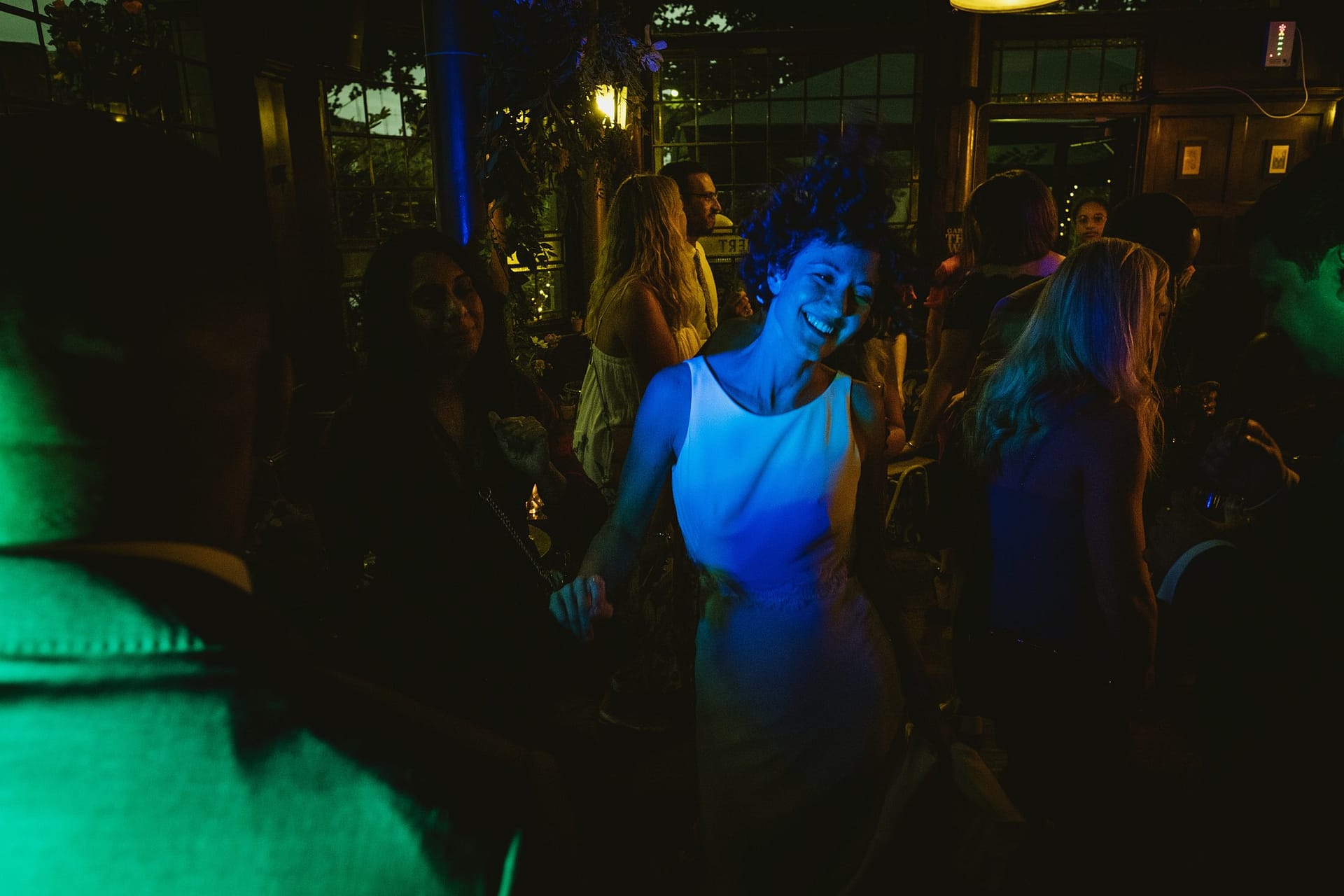 bride lit by blue light dancing at her wedding reception Prince Albert pub in london