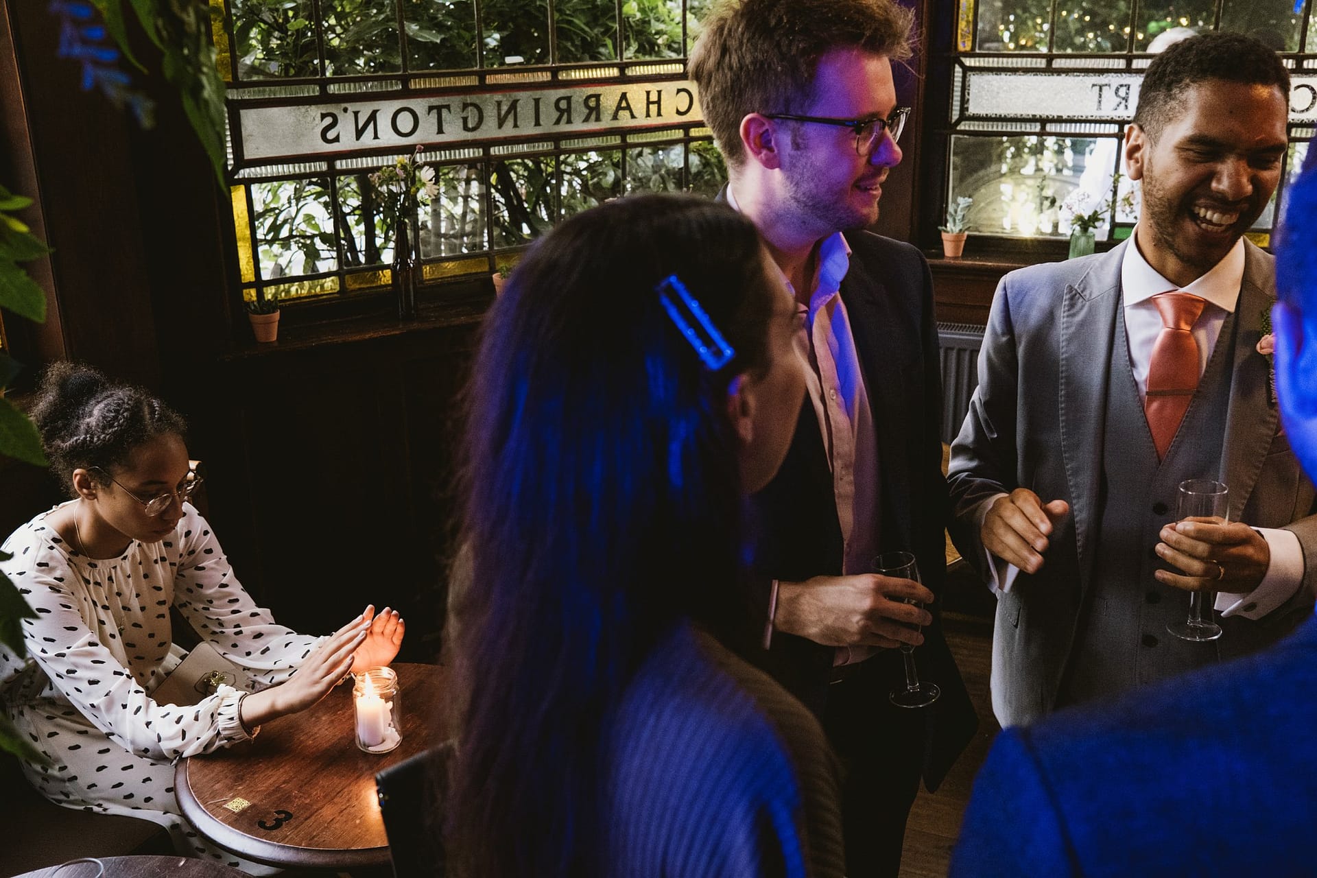 groom with wedding guests flower girl warming hand on decorative candle at Prince Albert pub