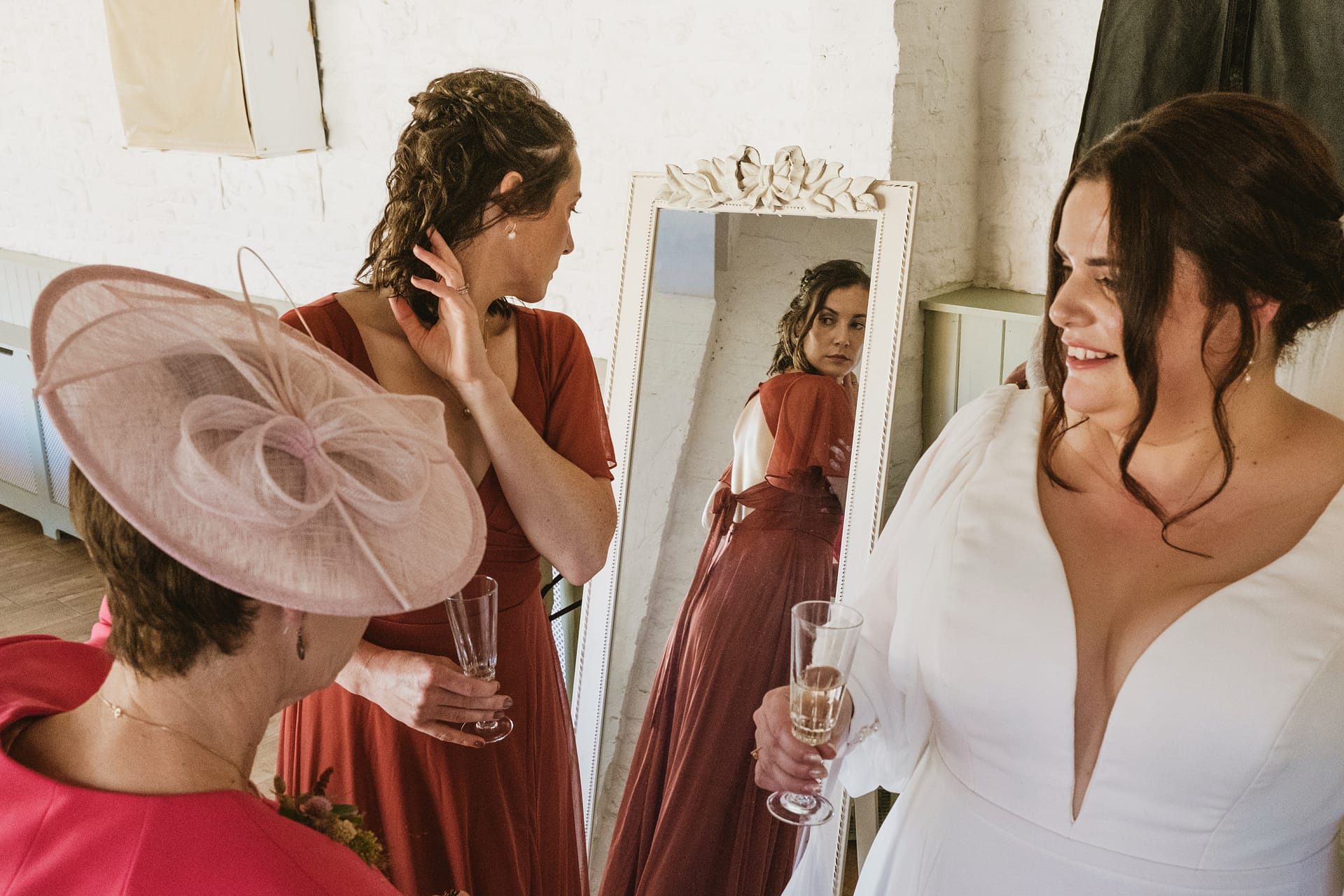 Women in dresses with glasses, reflected in mirror.