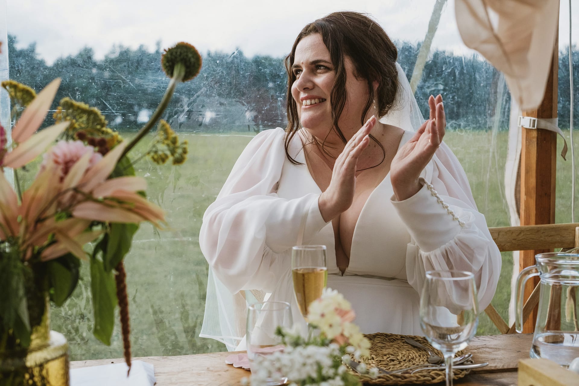 Bride clapping with champagne at wedding table