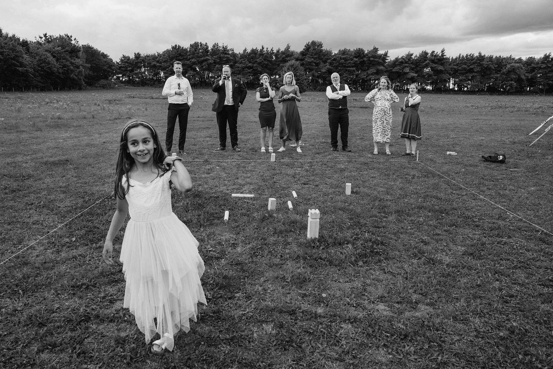 Girl in white dress playing outdoor game, smiling.