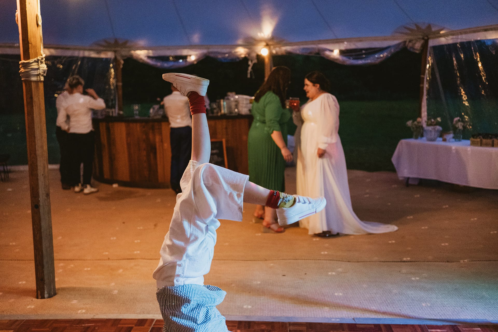 Child doing headstand at wedding reception party.