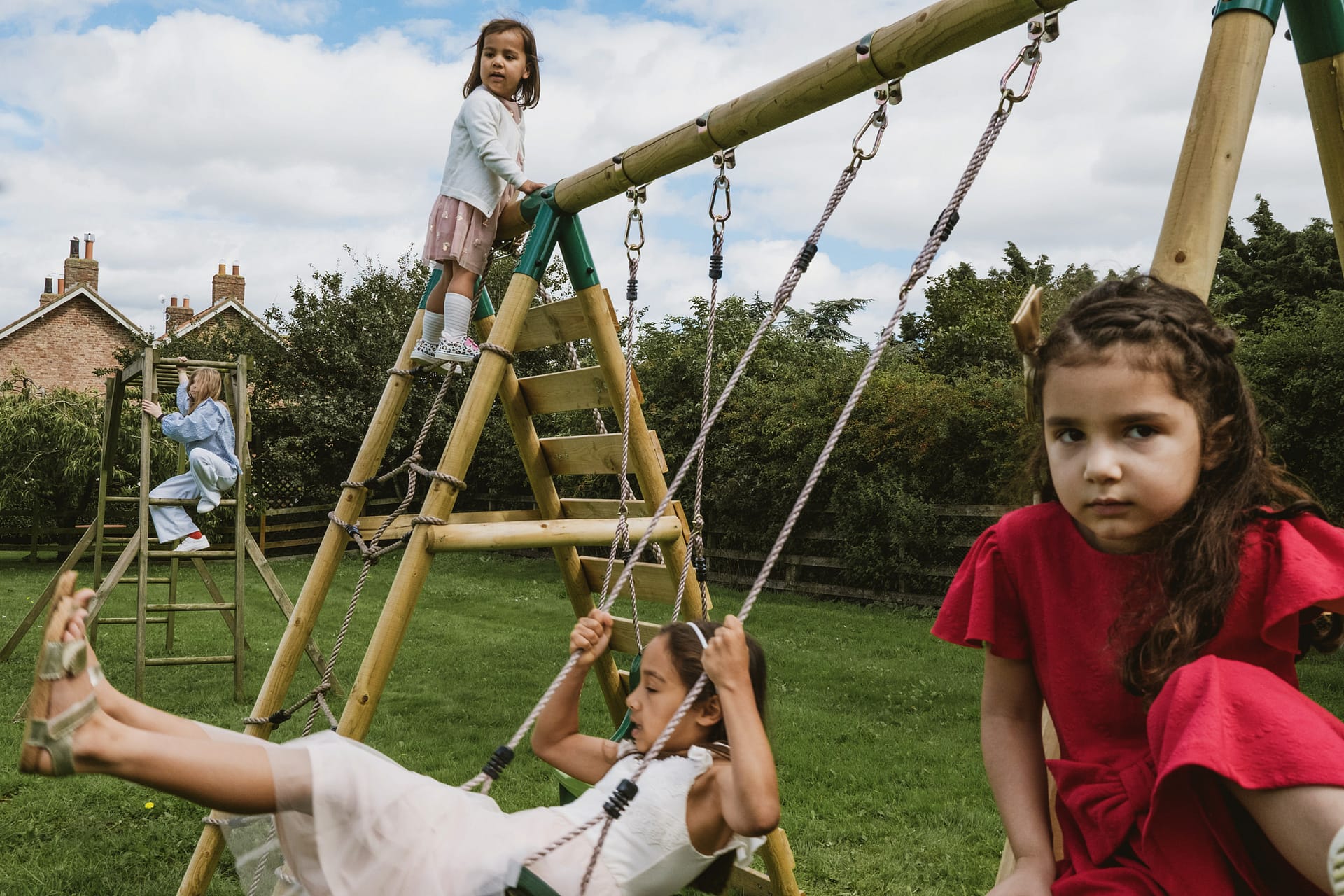 Children playing on wooden playground equipment outside.