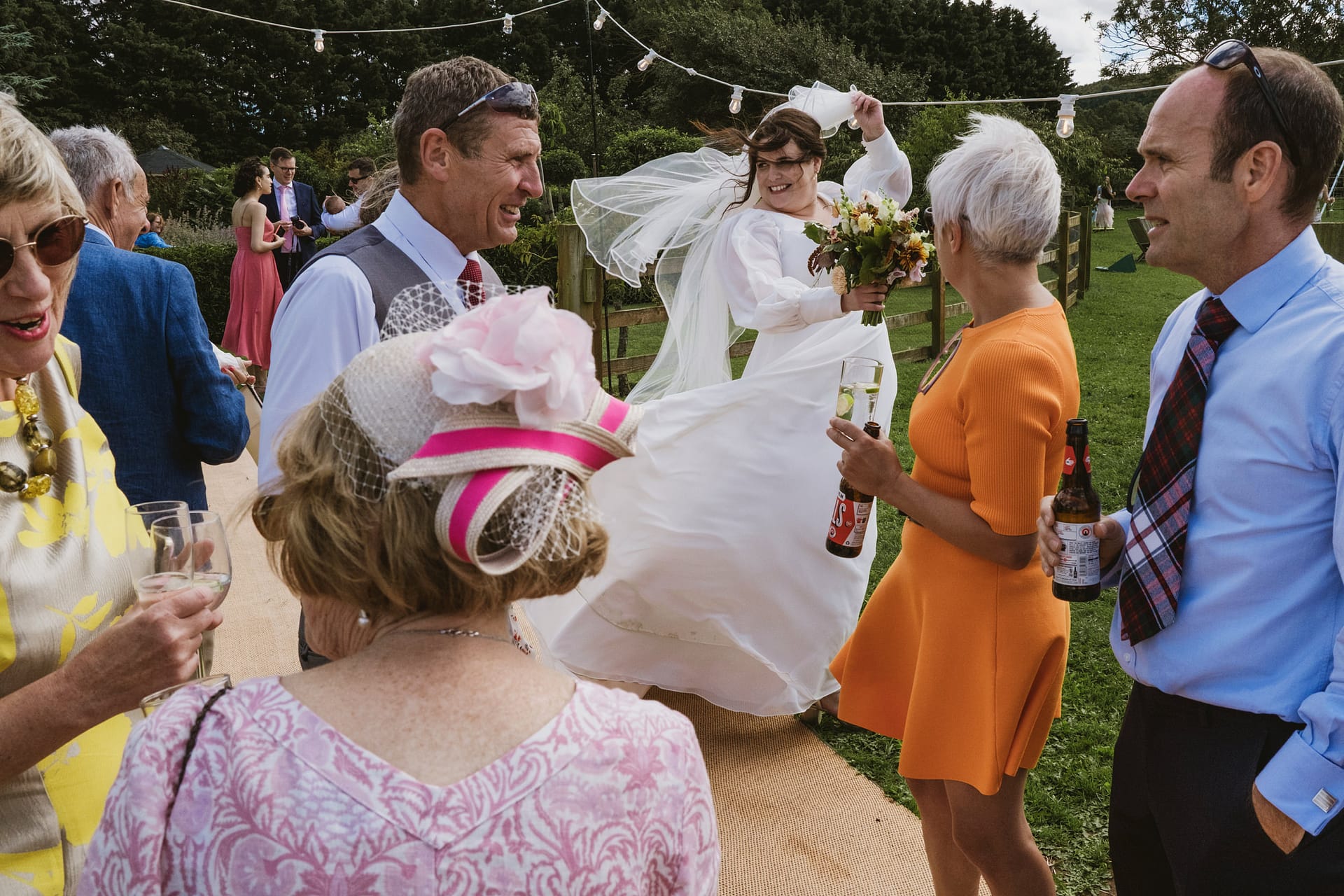 Bride dancing joyfully at outdoor wedding reception.