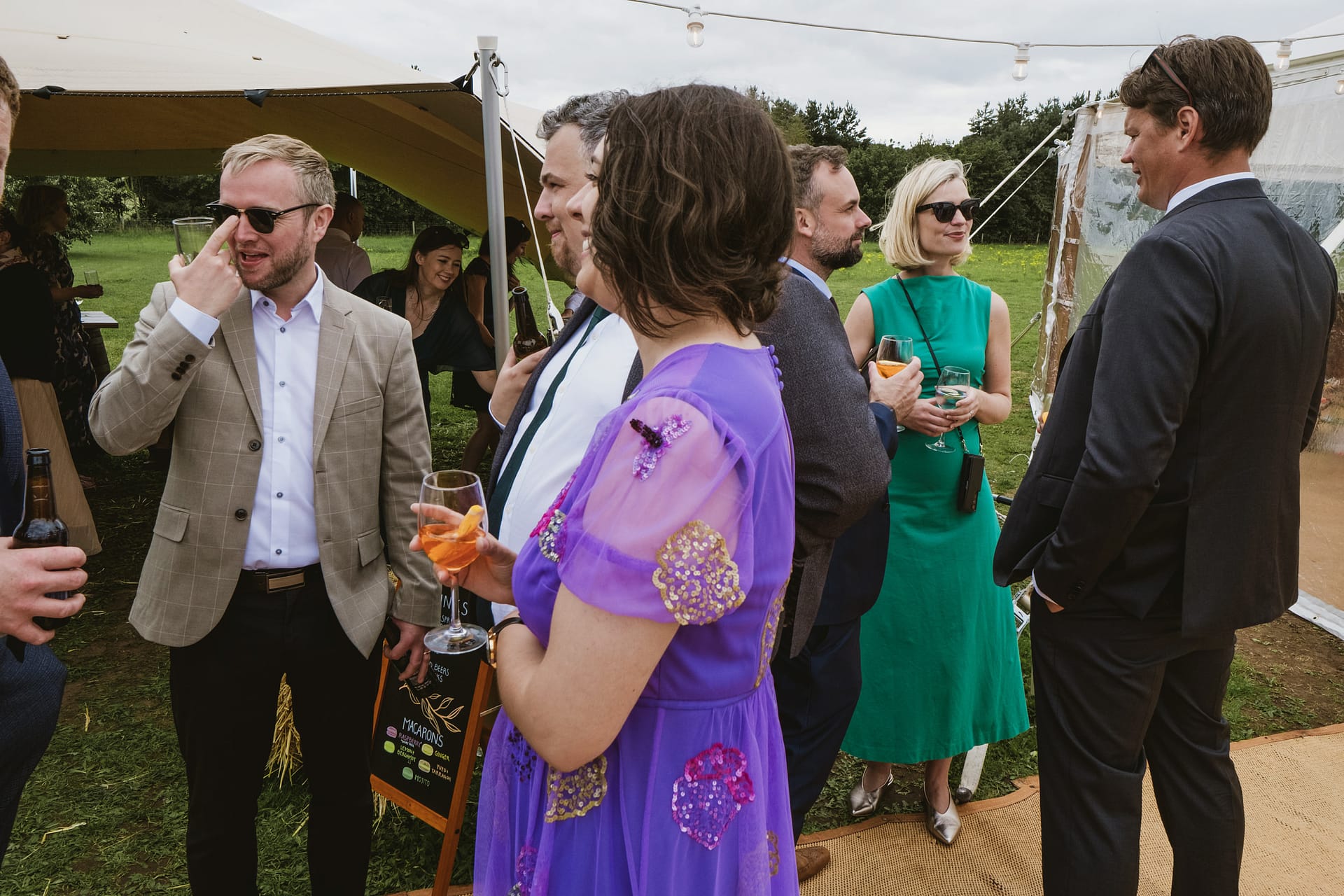 Guests socialising at outdoor event, colourful outfits.