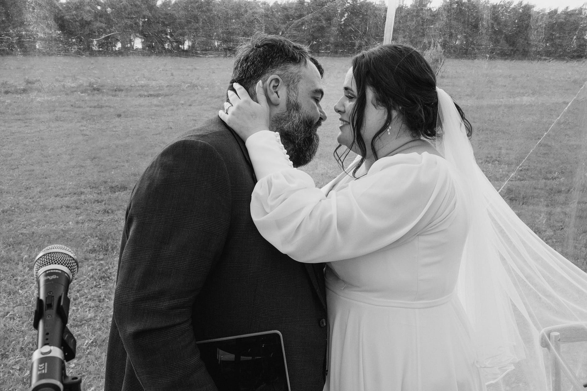 Bride and groom embrace tenderly outdoors.