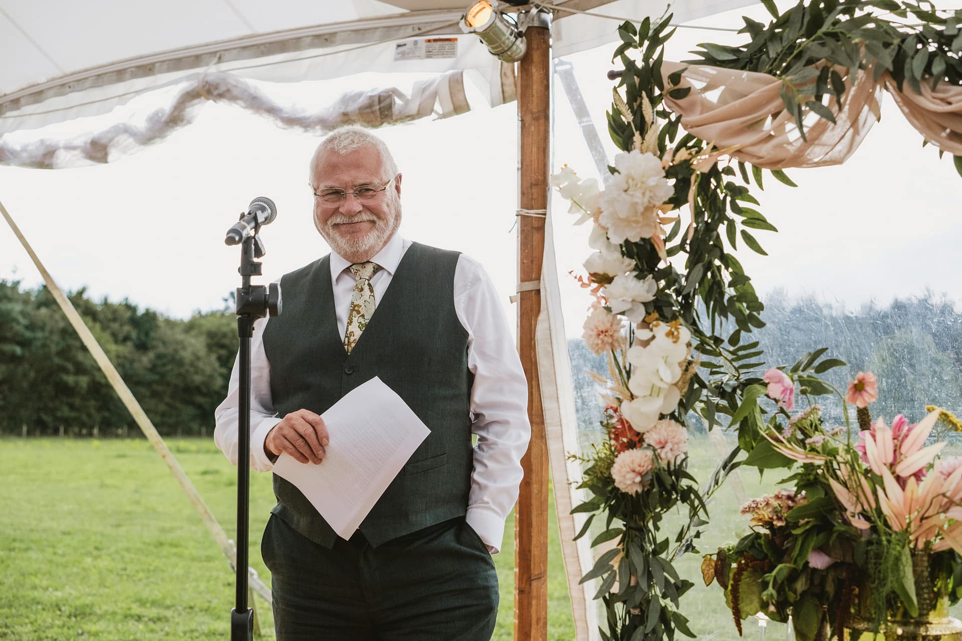 Man delivering speech at outdoor wedding ceremony