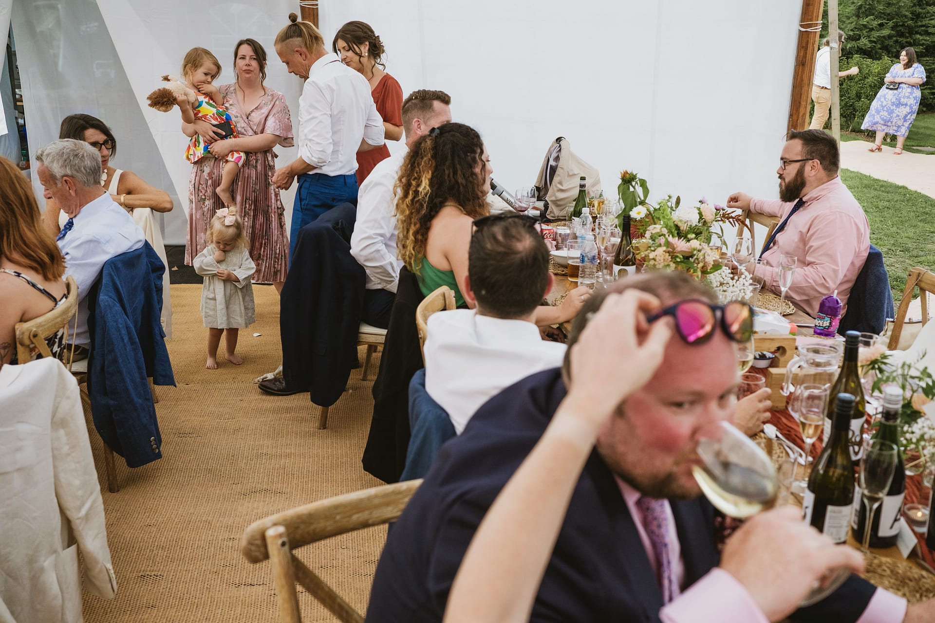 Guests enjoying outdoor wedding reception with children playing.