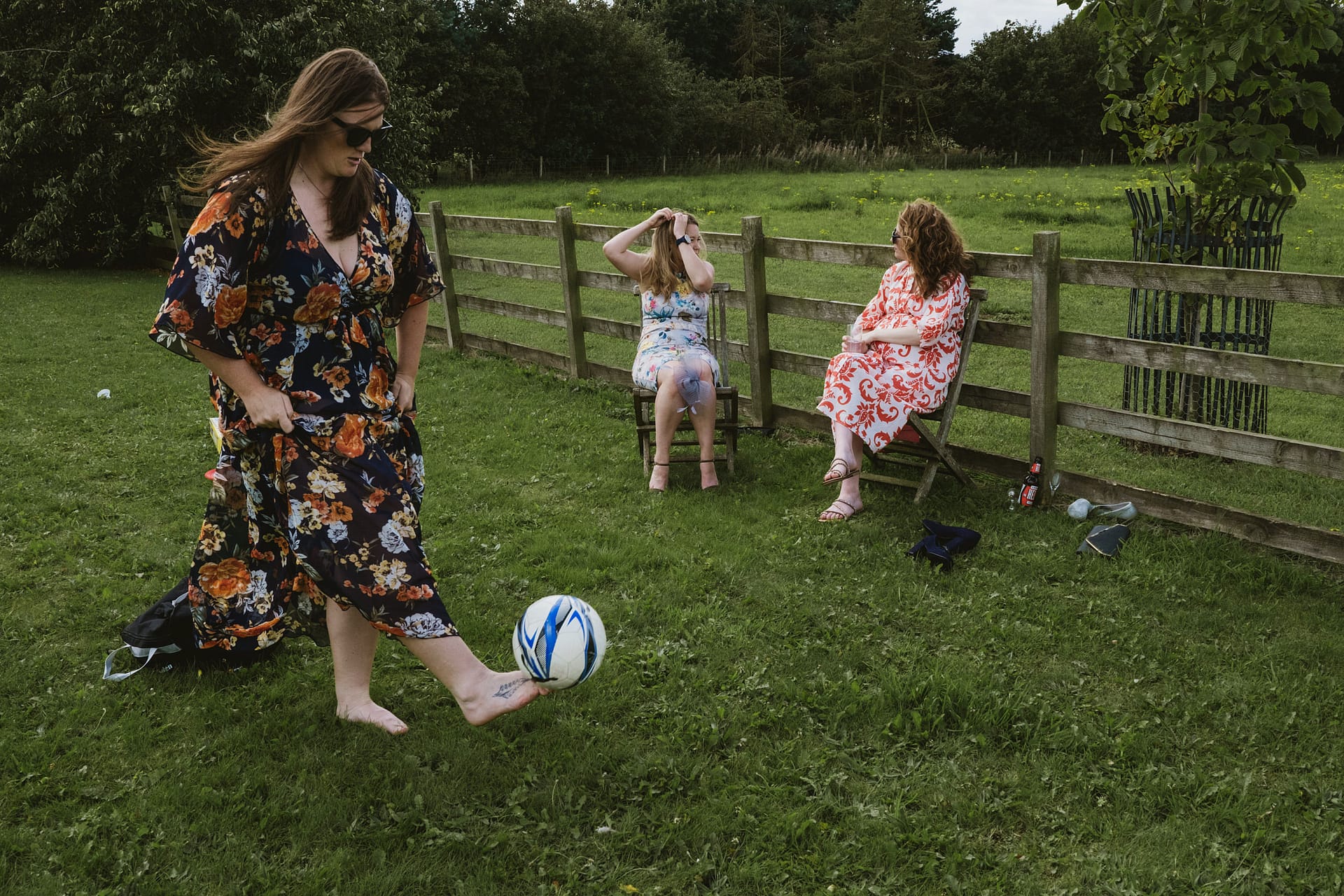 Woman playing barefoot football in floral dress