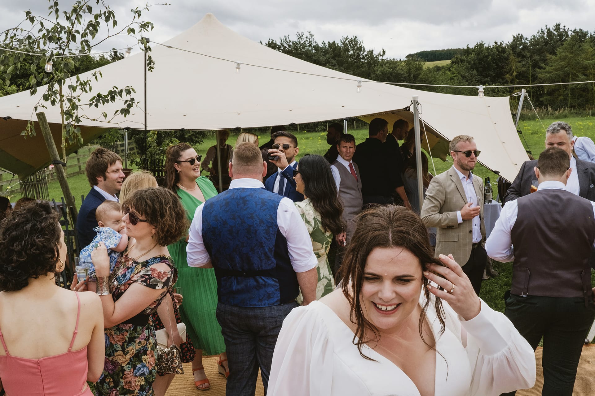 Guests enjoying outdoor gathering under tent.