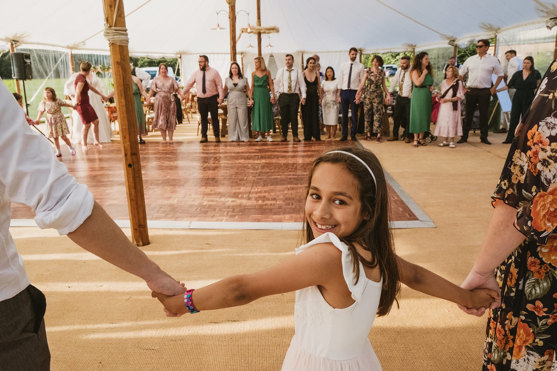 Girl holding hands at wedding dance circle.