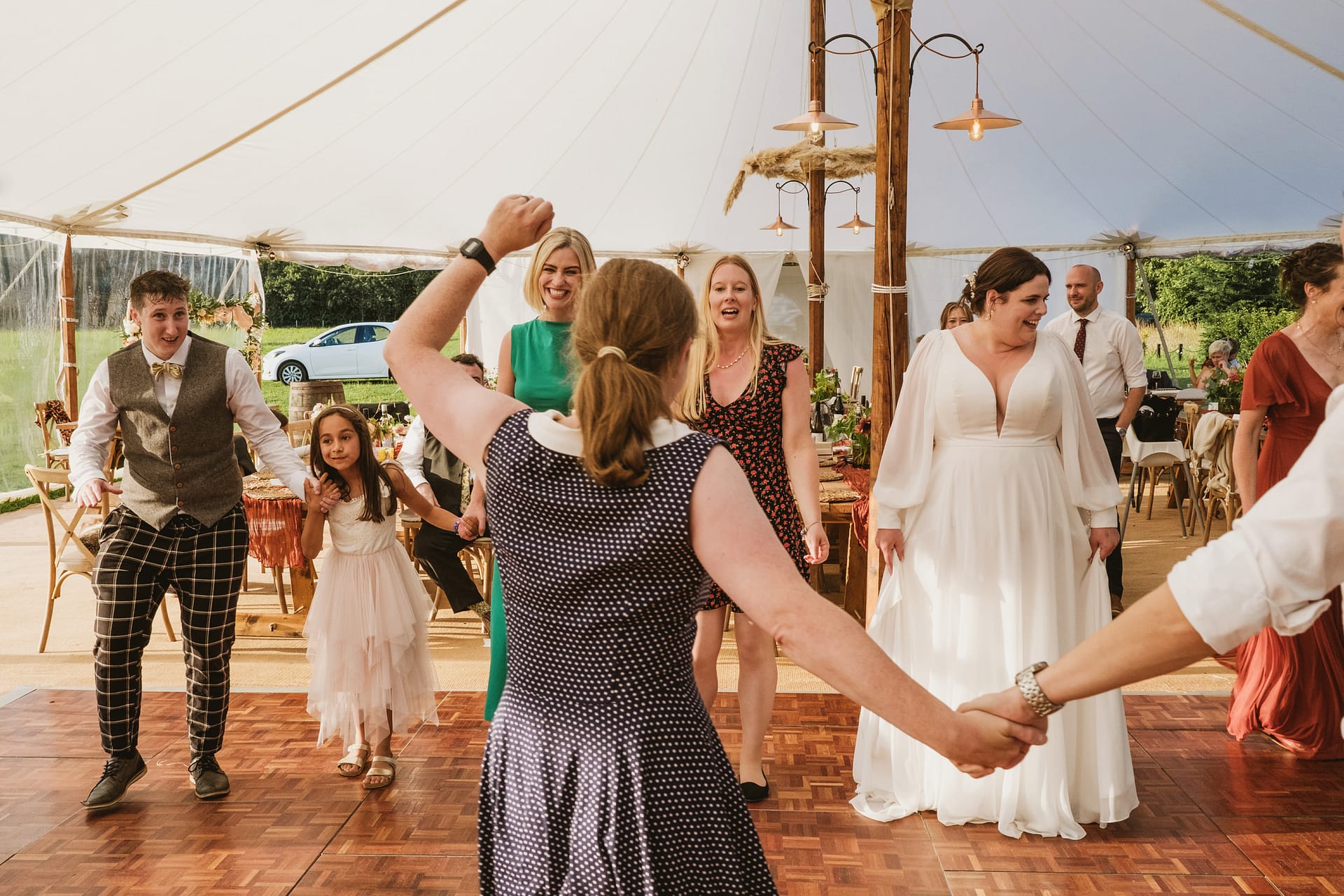 Guests dancing at wedding reception under marquee.