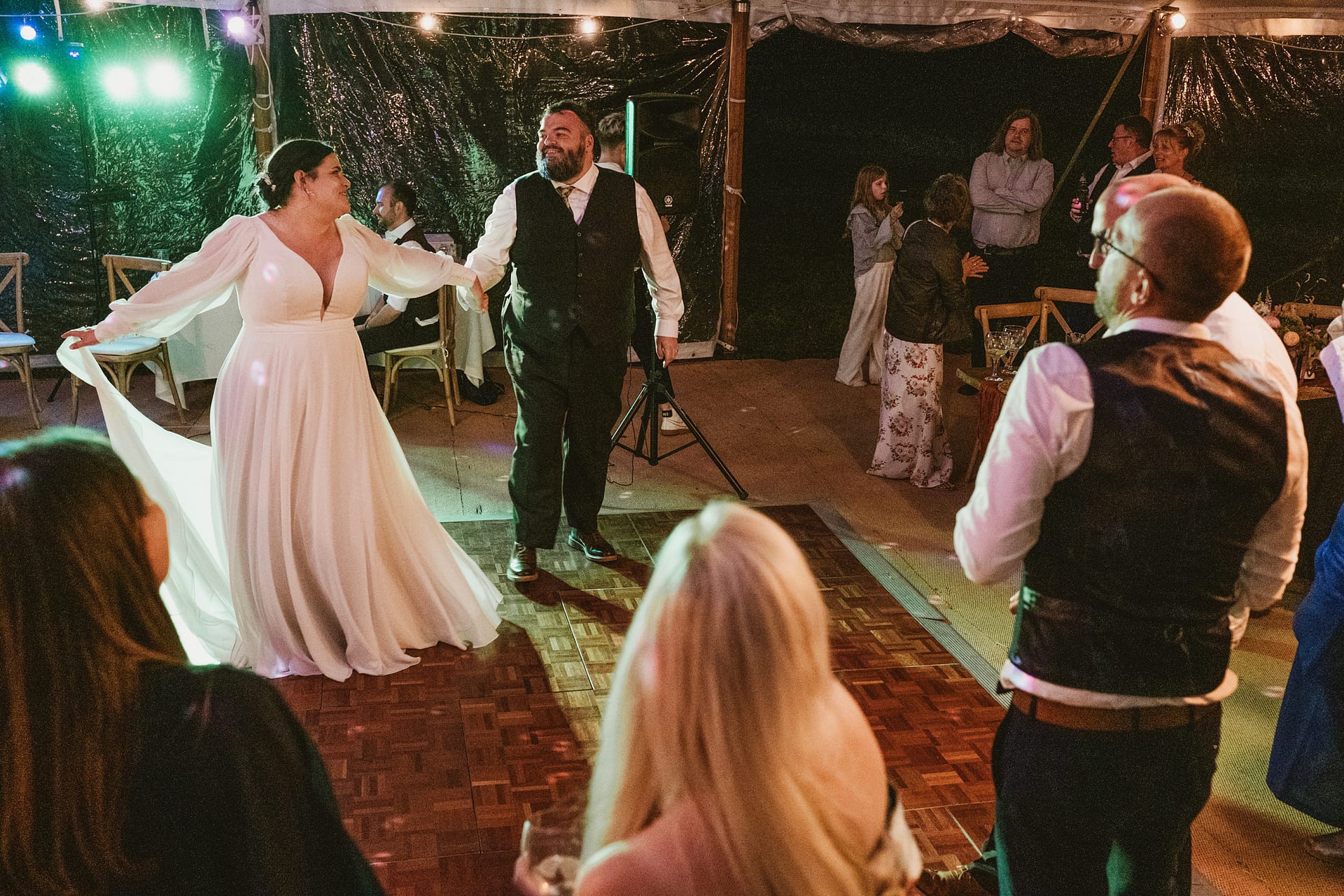 Couple dancing at wedding reception with guests watching.