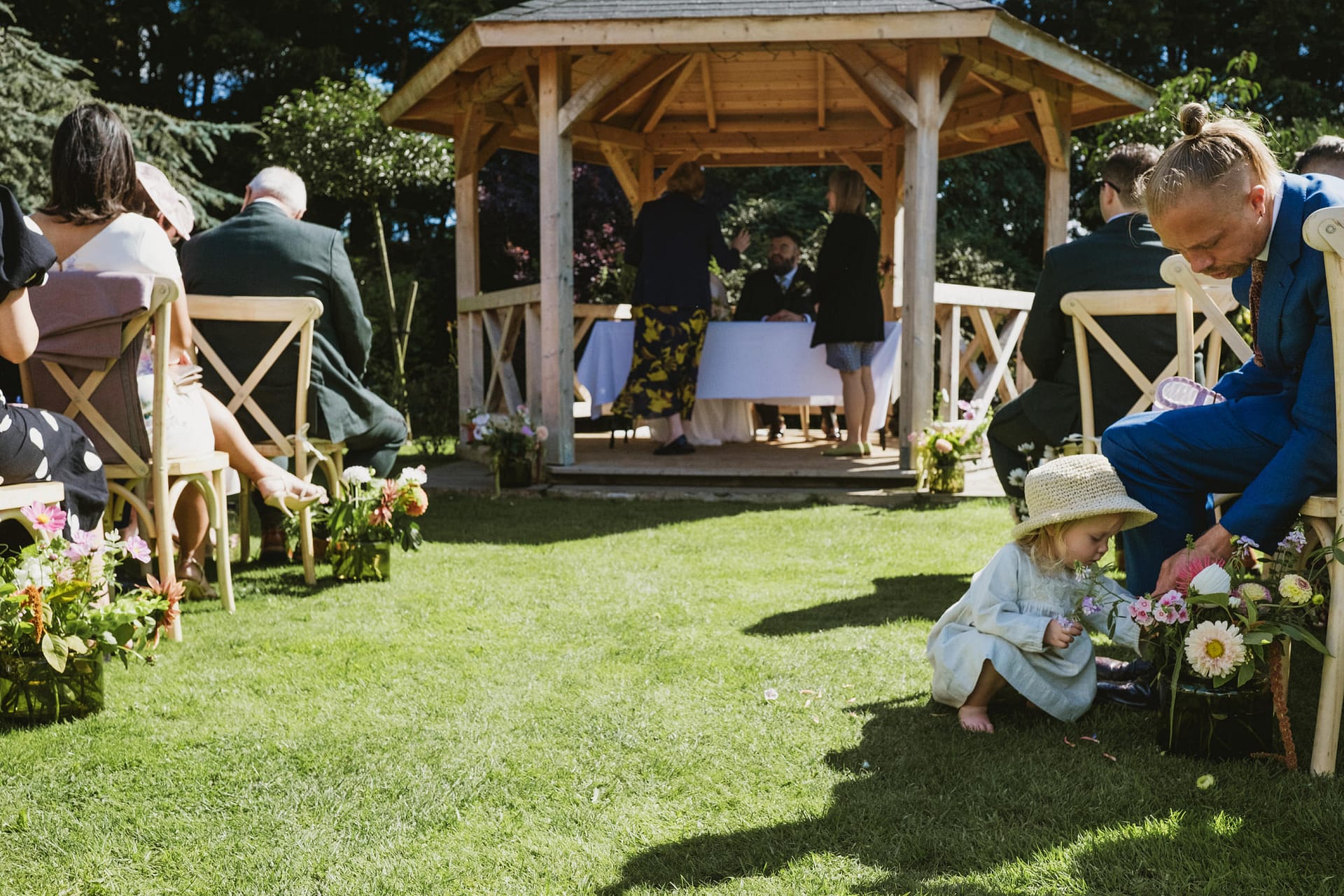 Child in summer dress at outdoor wedding ceremony.