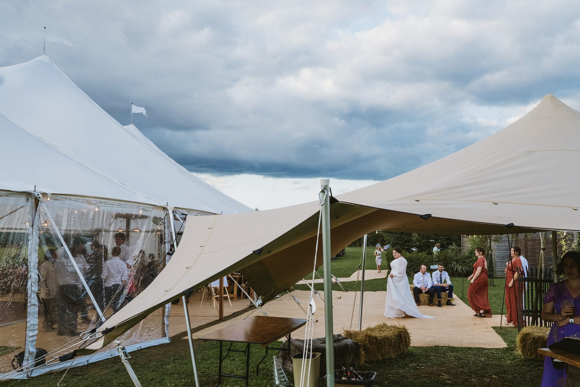 Outdoor wedding with tents, guests in colourful attire.