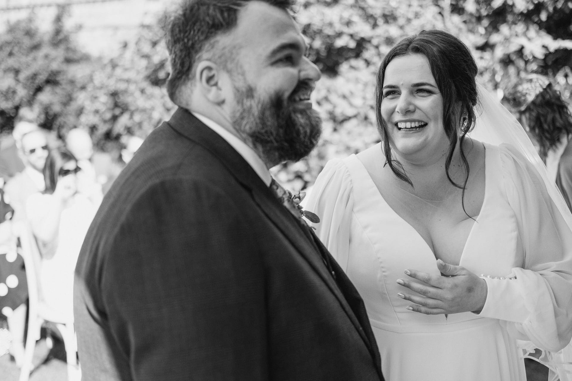 Smiling couple at wedding ceremony outside.