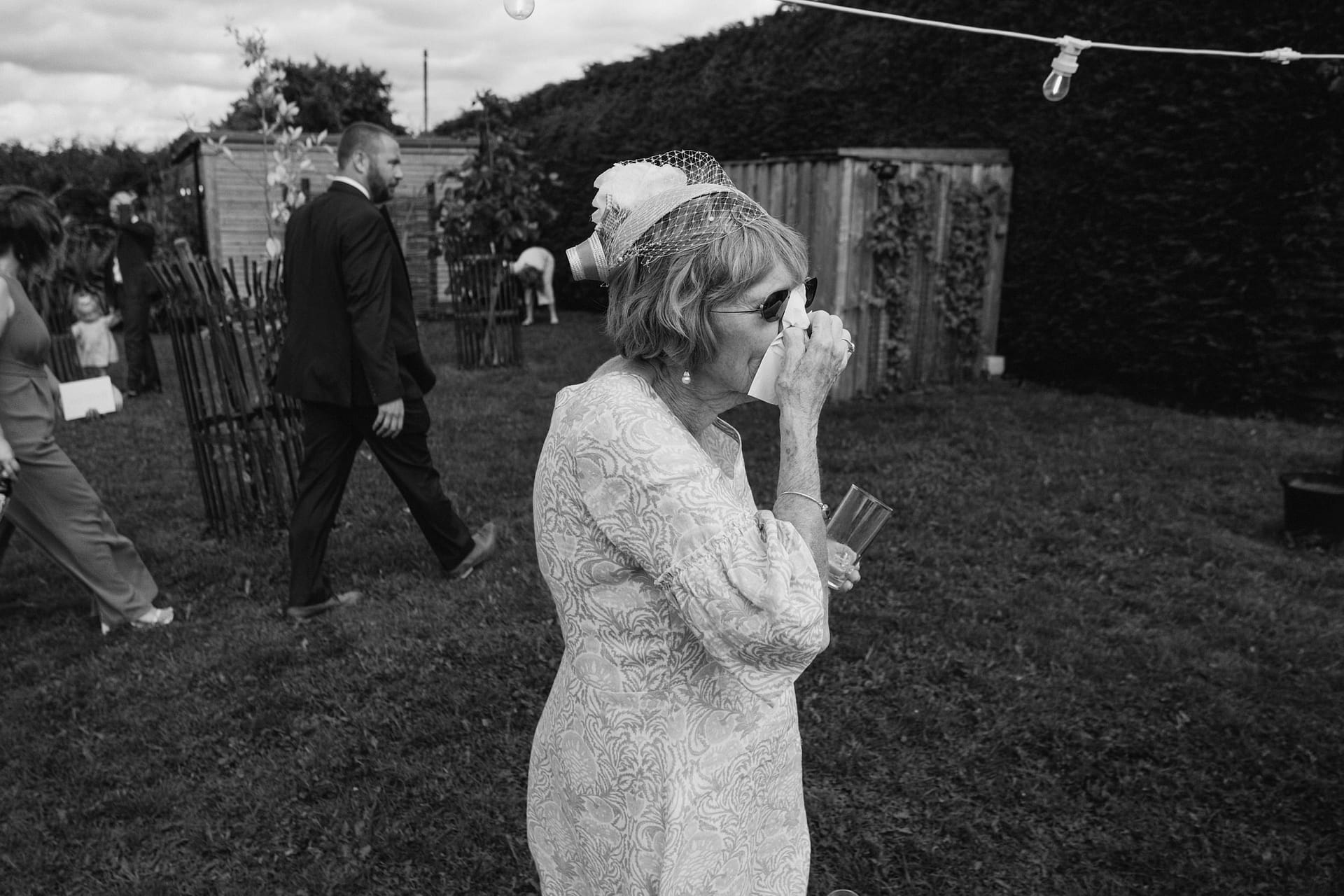 Woman wiping tears at outdoor event.