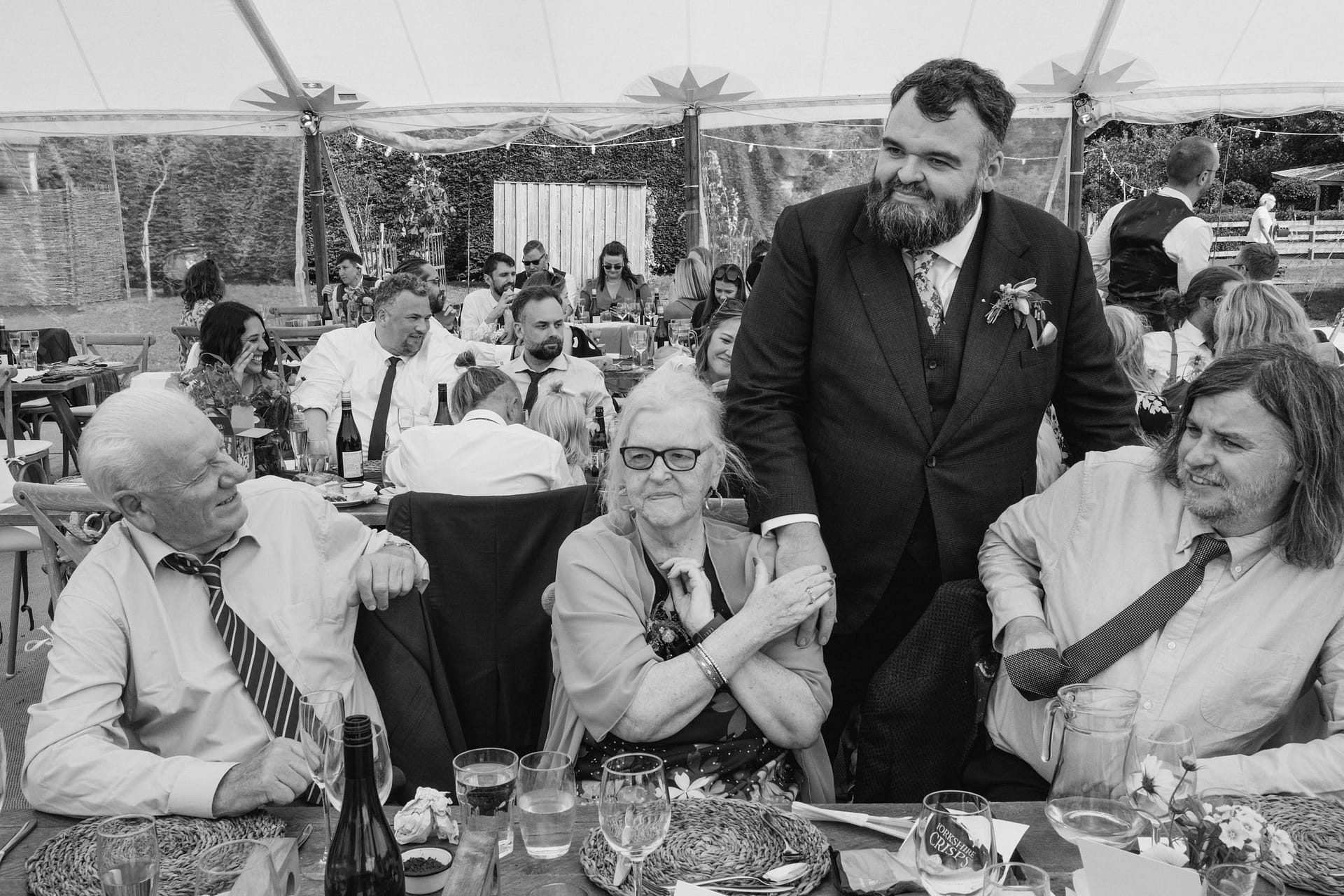 Wedding guests smiling at reception table gathering.