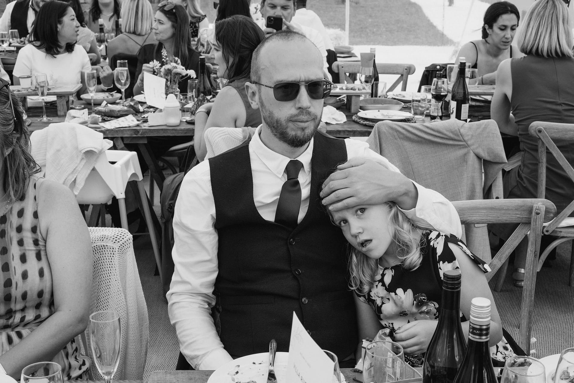 Man and child at crowded outdoor dining event.