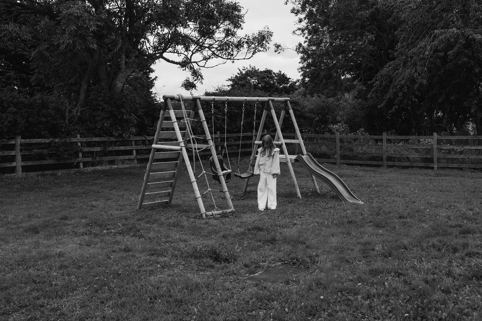 Child standing by a playground swing.