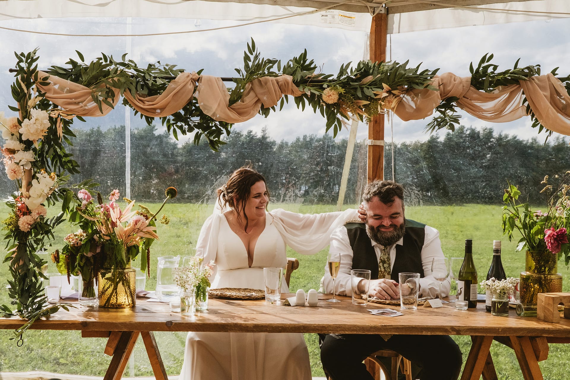 Bride and groom laughing at rustic wedding table.