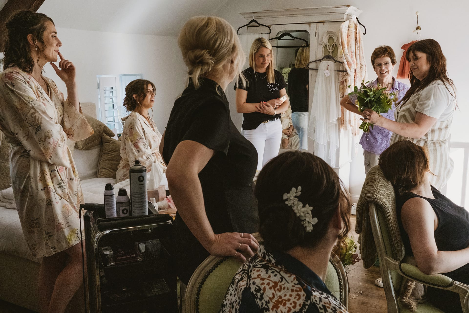 Bridesmaids getting ready before wedding in cosy room.