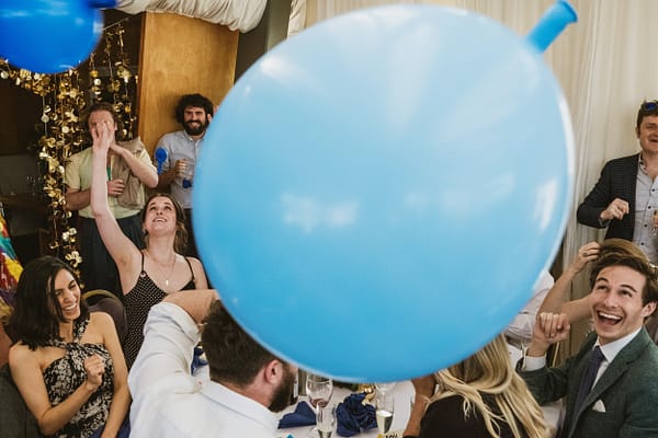 documentary wedding photography - blue balloon in the foreground fills the centre of the frame whilst guests celebrate around it in the background