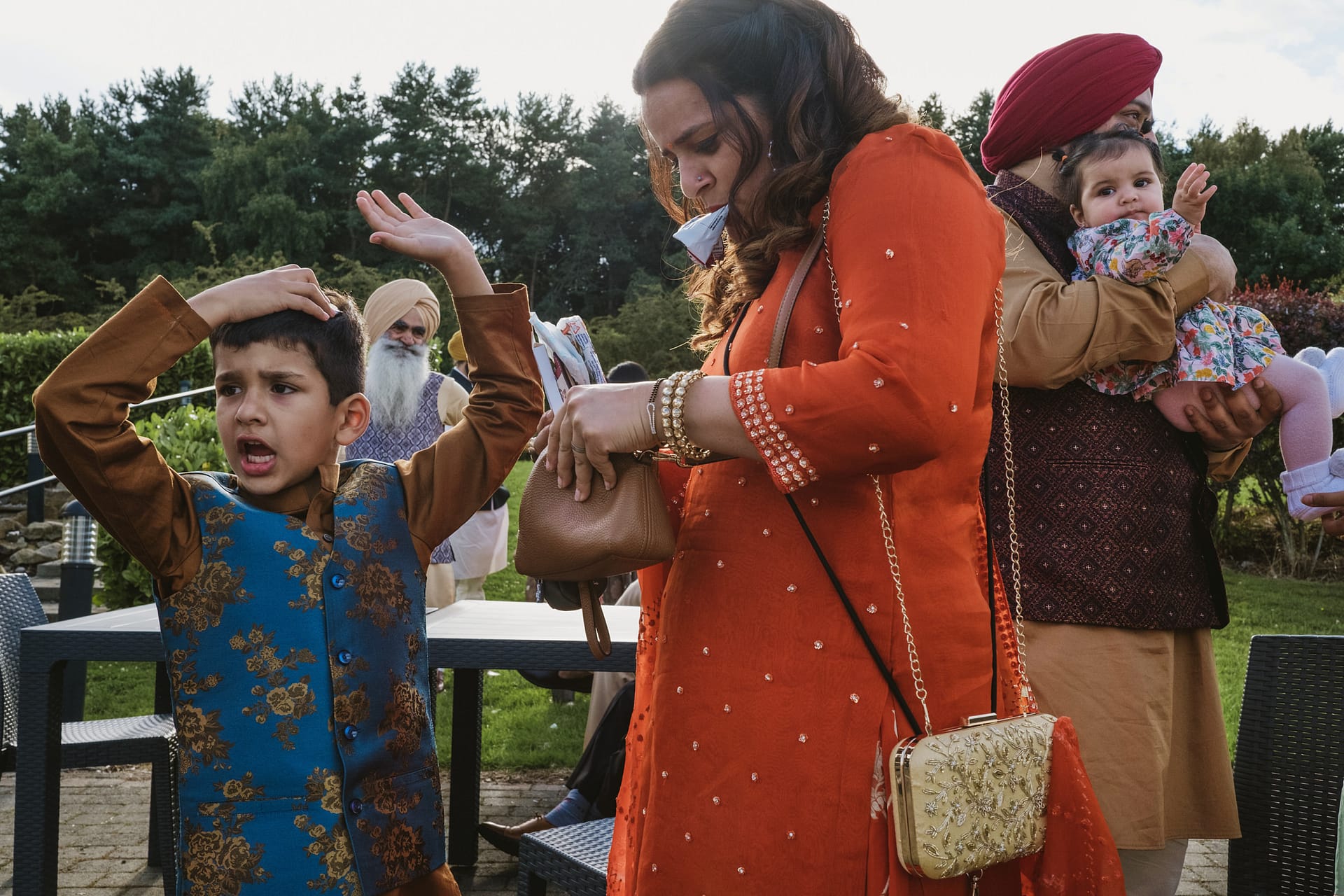 Family outside, child gesturing, mother holding purse.