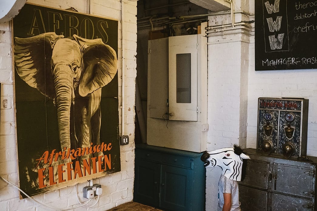 Candid wedding photograph - boy in zebra mask looks at poster of an elephant at London's One Friendly Place