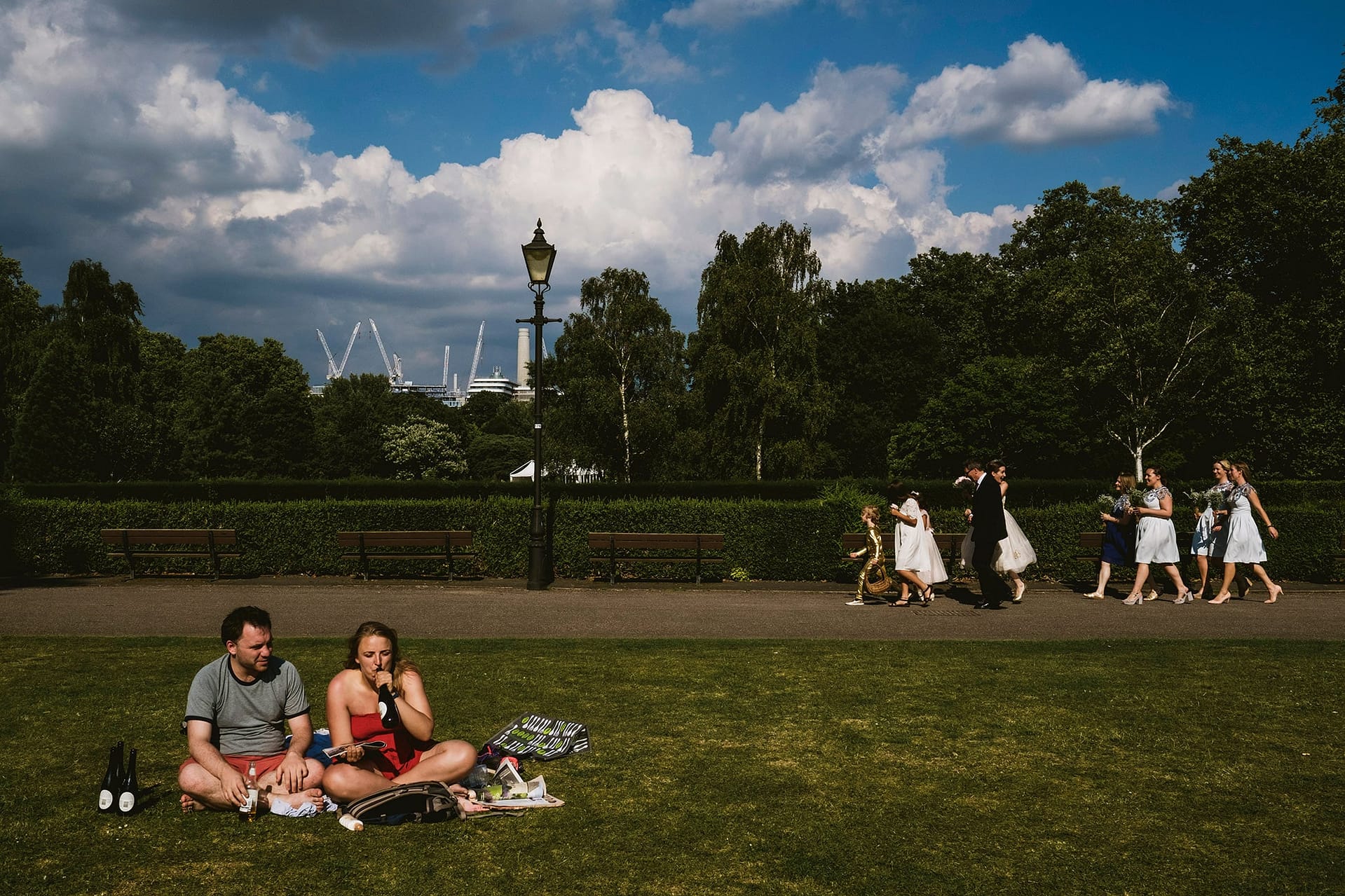 Battersea Park. in London bride walking through the park guests drinking nearby