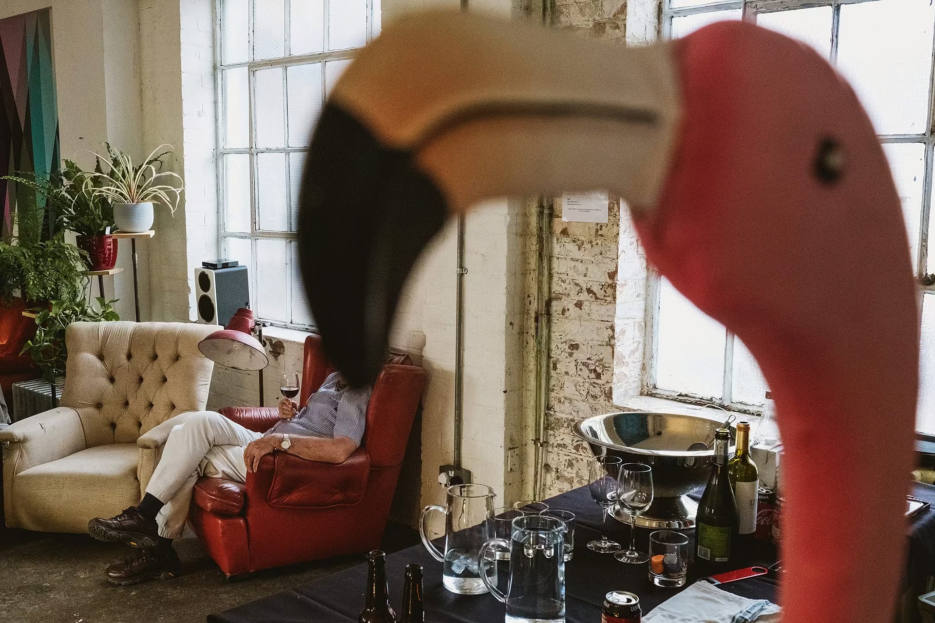 A guest's face is hidden by the beak of an artificial flamingo during a wedding at London's One Friendly Place