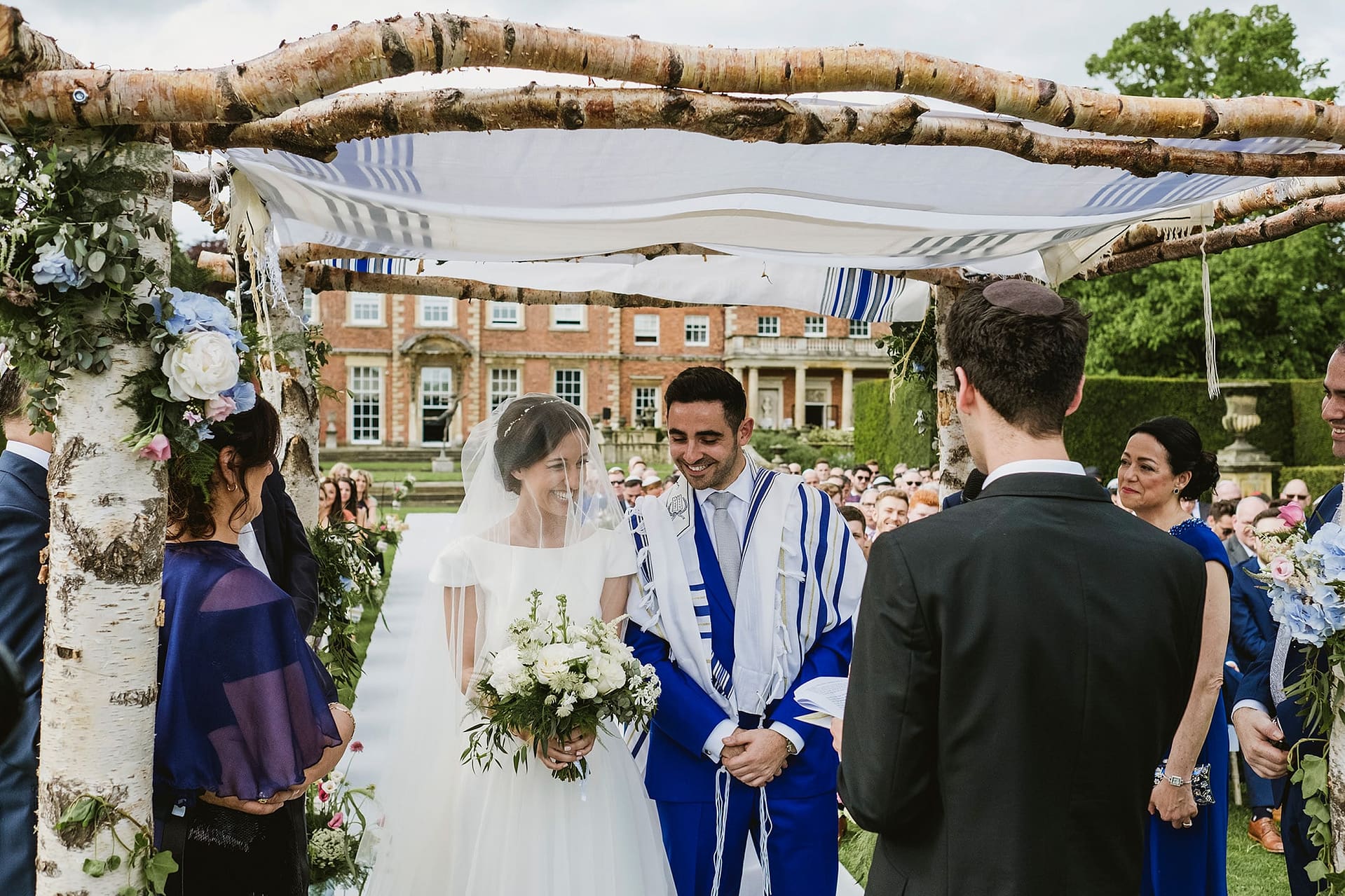 Newby Hall outdoor Jewish ceremony. Bride and groom smiling during the ceremony.