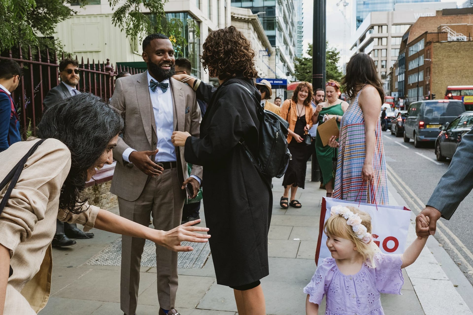 A group of people walking down a street in St Botolph without Aldgate with a little girl.