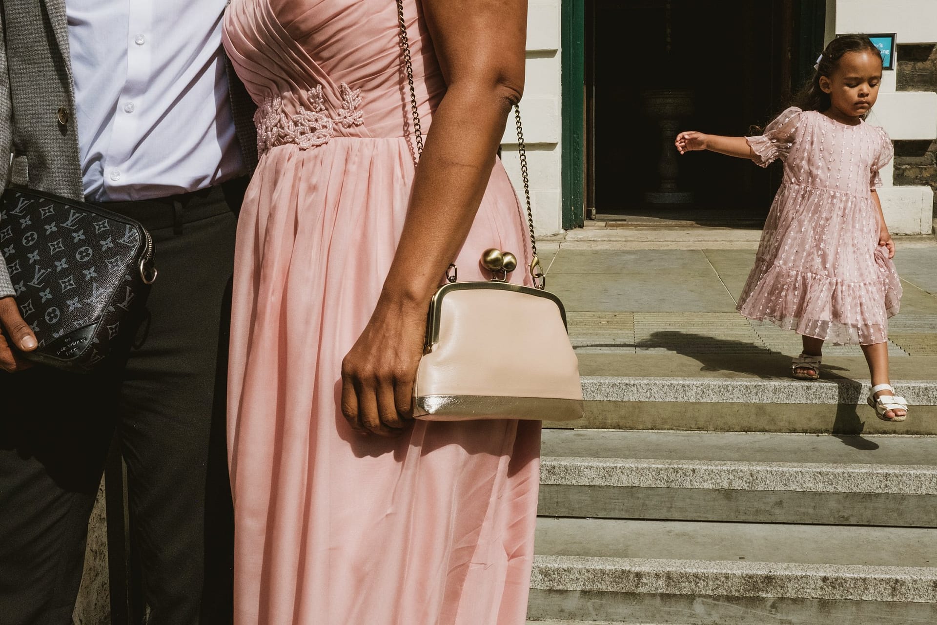 A woman and a girl, both wearing pink dresses, standing in front of St Botolph without Aldgate.