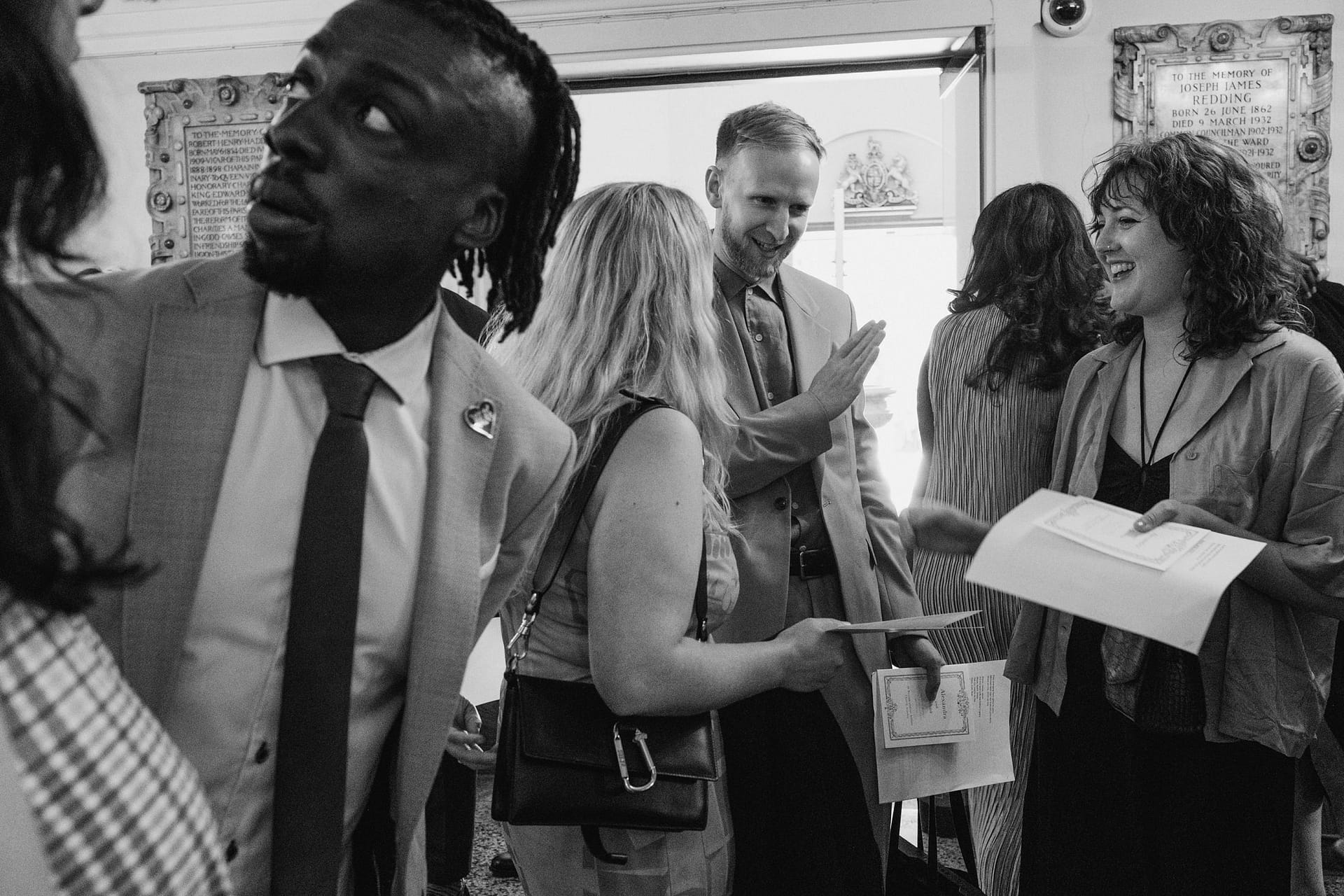 A black and white photo of a group of people talking at St Botolph without Aldgate.