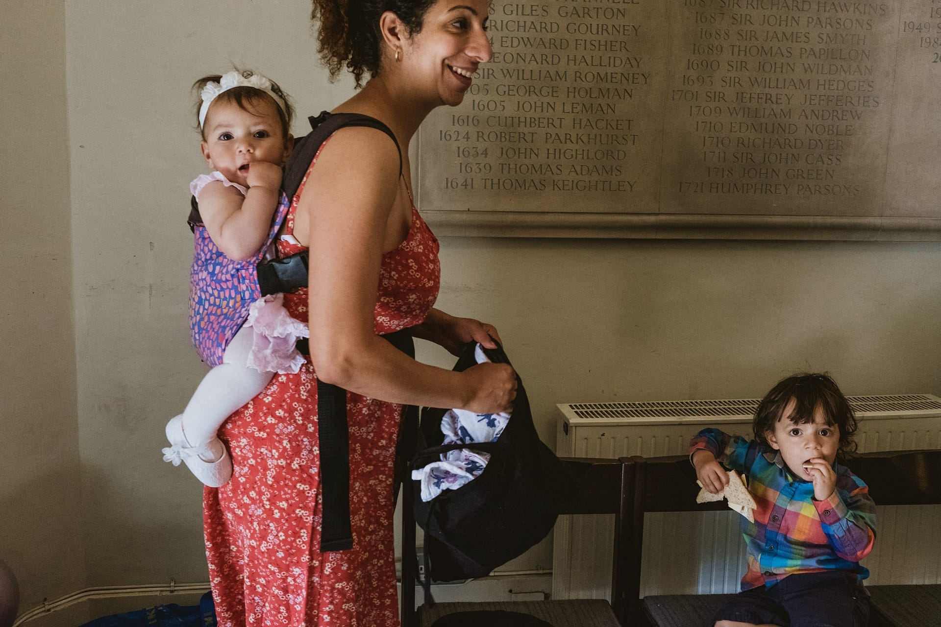 A woman is holding a baby in a baby carrier near St Botolph without Aldgate.