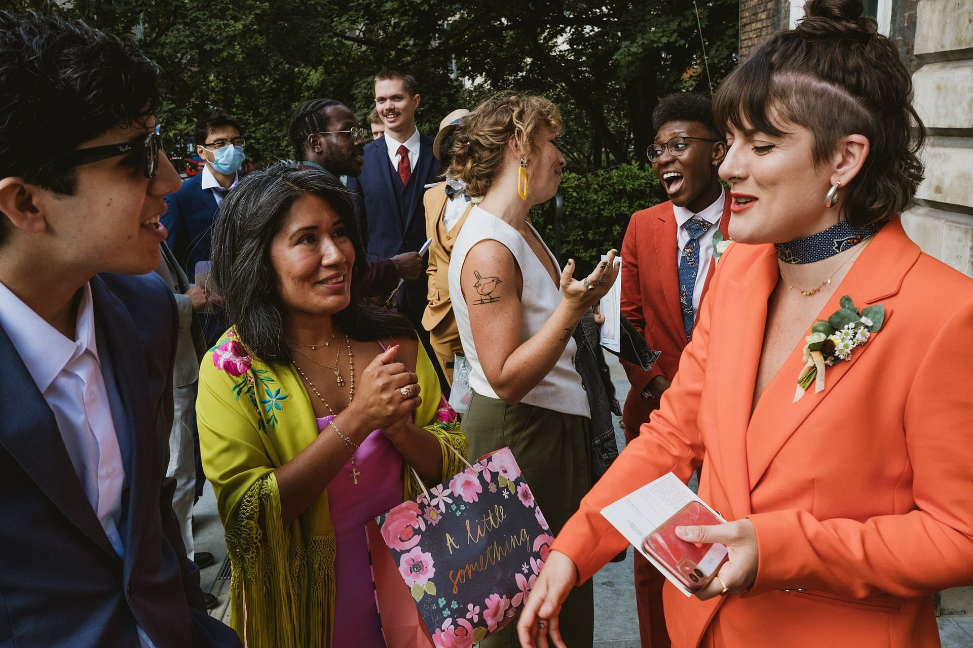 A woman in an orange suit is talking to a group of people at St Botolph without Aldgate.