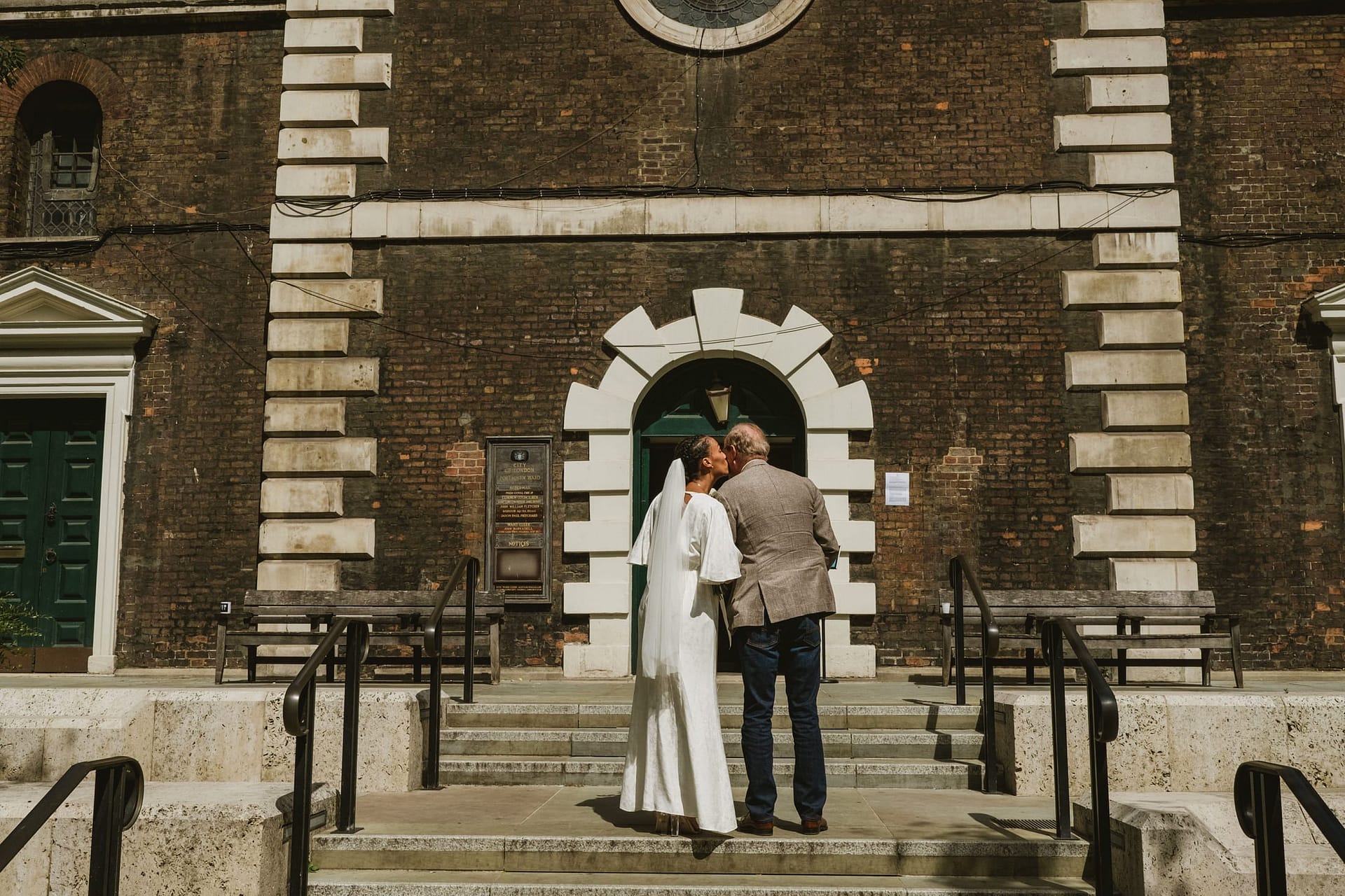 A bride and father of the bride wait outside St Botolph without Aldgate church